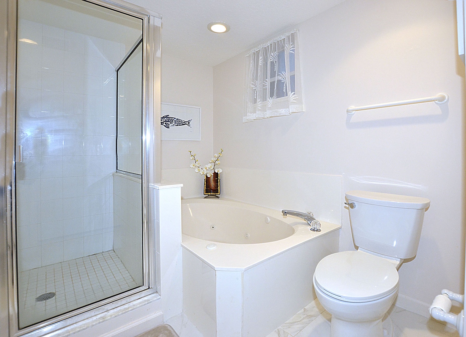 Unwind in your spacious Primary Bathroom featuring a luxurious tub and glass-enclosed shower, thoughtfully appointed with charming coastal touches.