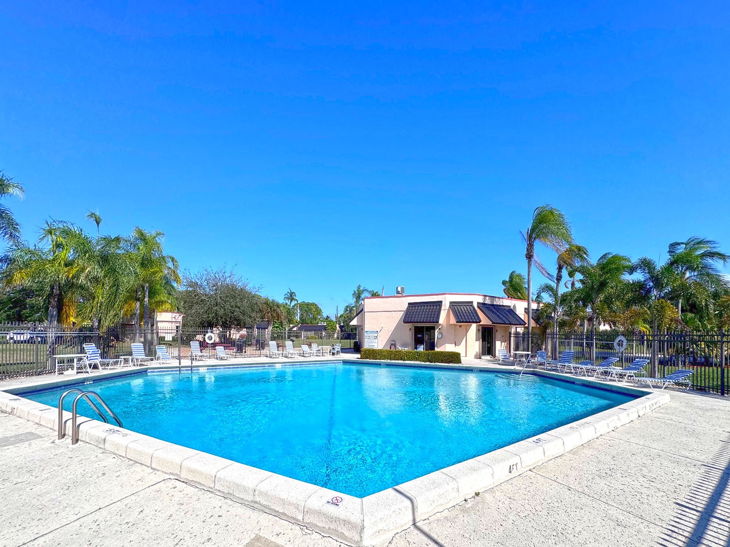 Crystal-clear pool surrounded by swaying palms creates your perfect tropical retreat under endless blue skies.