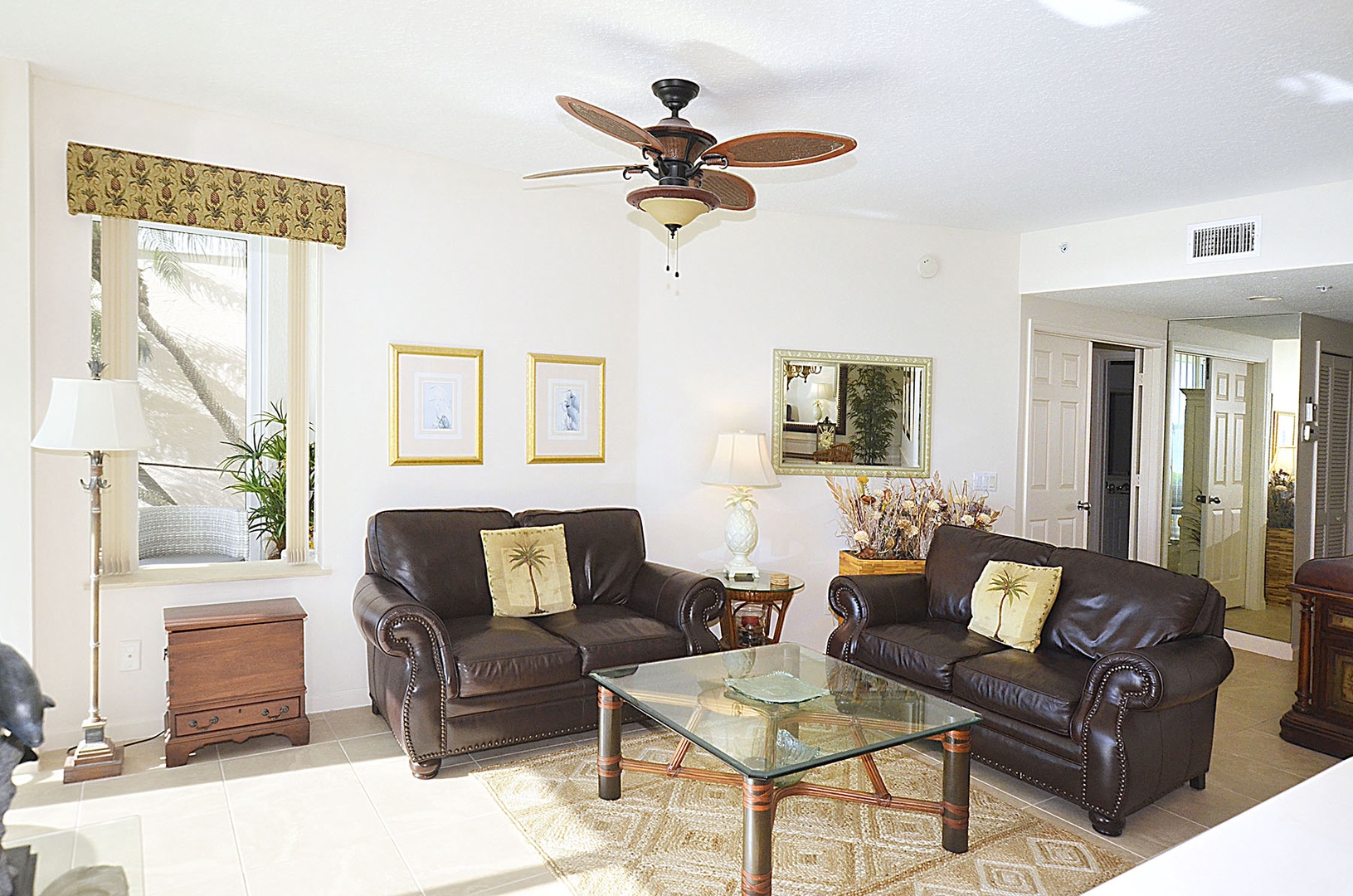 Relax in your elegant living room featuring rich leather seating and tropical touches that create the perfect retreat atmosphere.