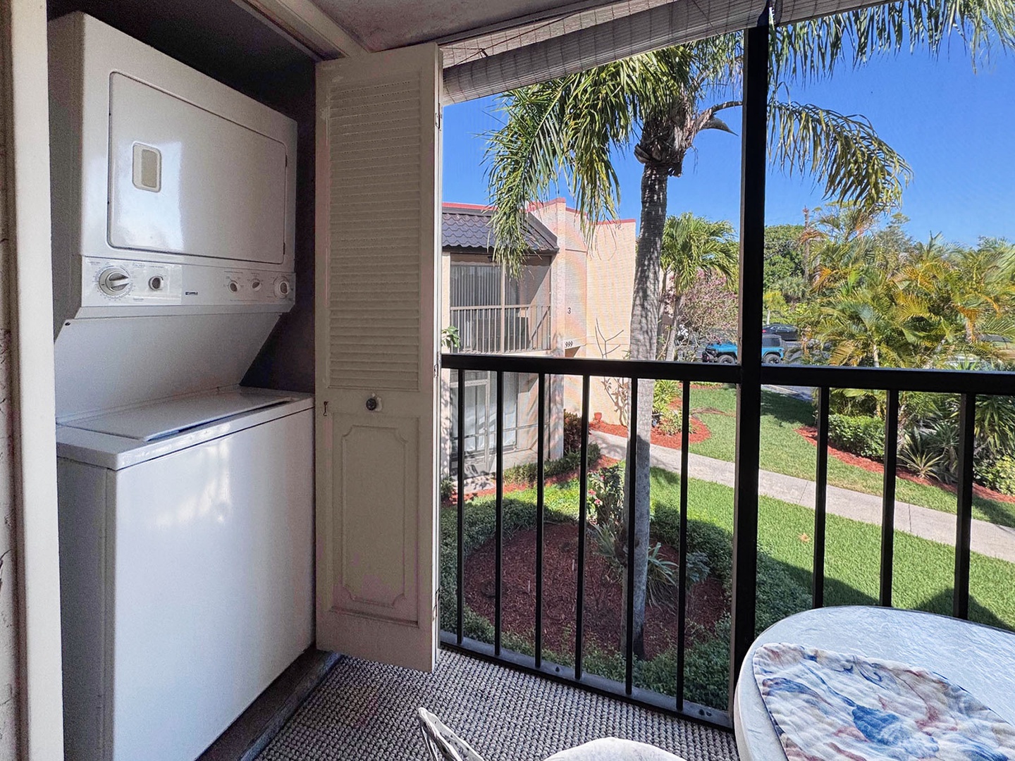 Your covered balcony features convenient washer-dryer combo and peaceful garden views with tropical palms.