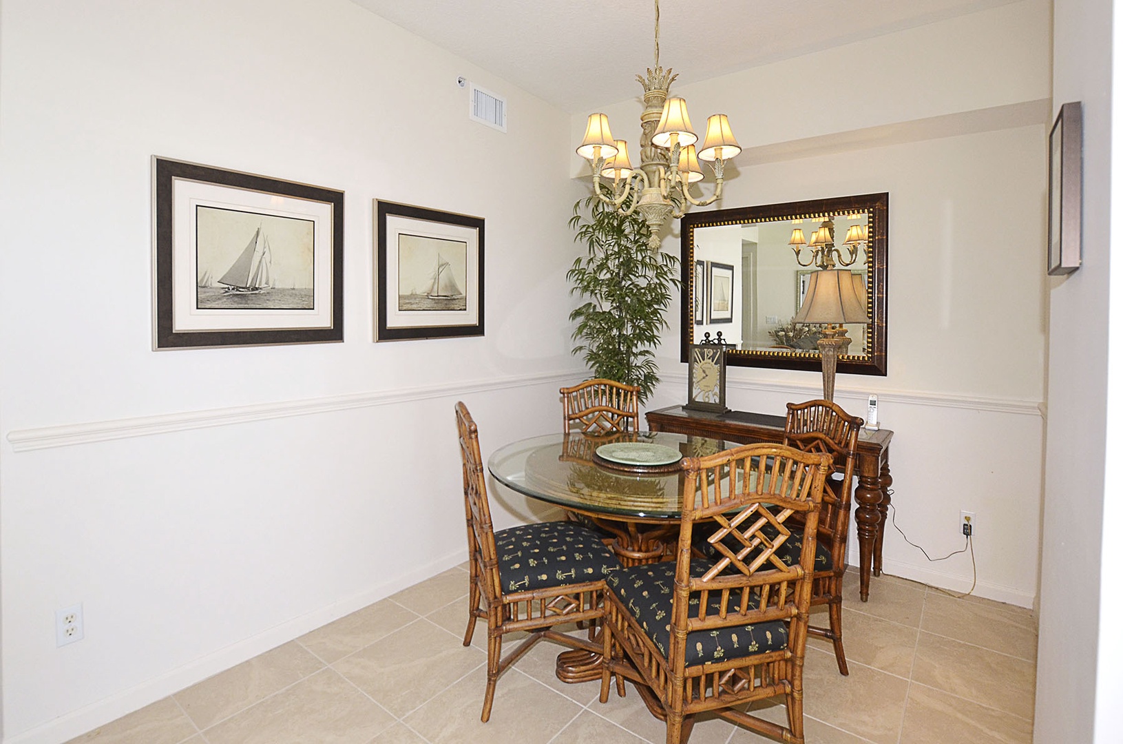 Your elegant dining room features a decorative chandelier, nautical artwork, and comfortable bamboo seating for casual meals together.