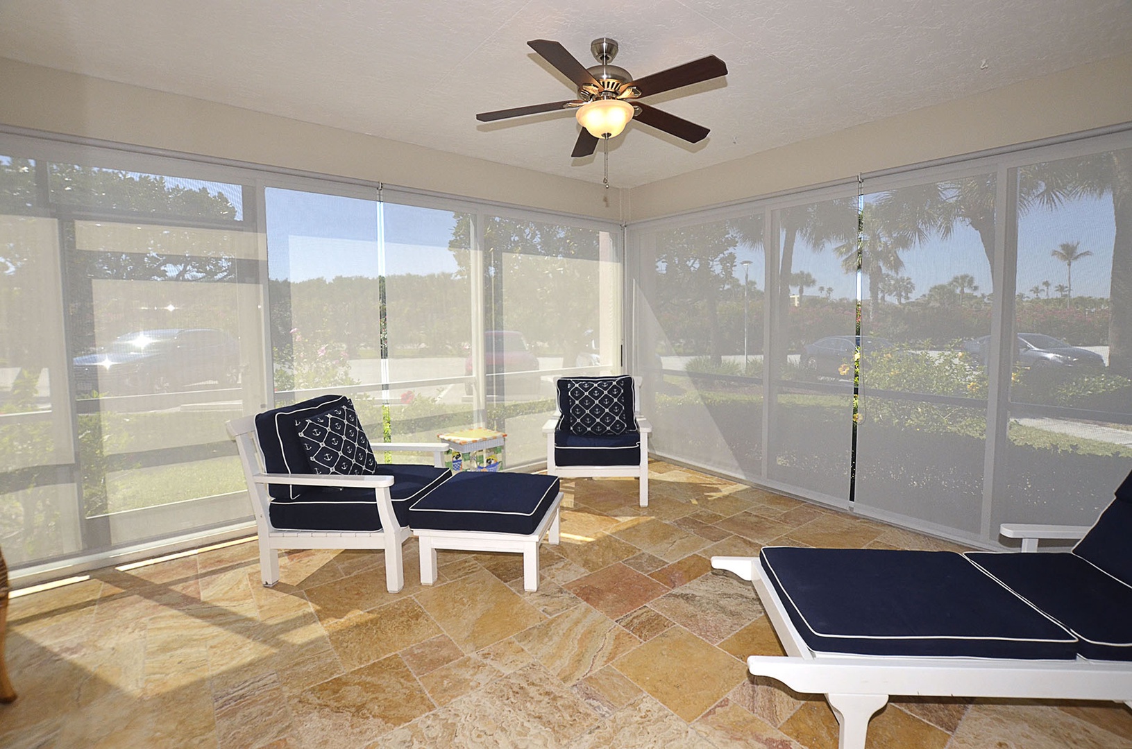The screened porch offers comfortable seating and garden views, perfect for relaxing while staying cool with the ceiling fan overhead.