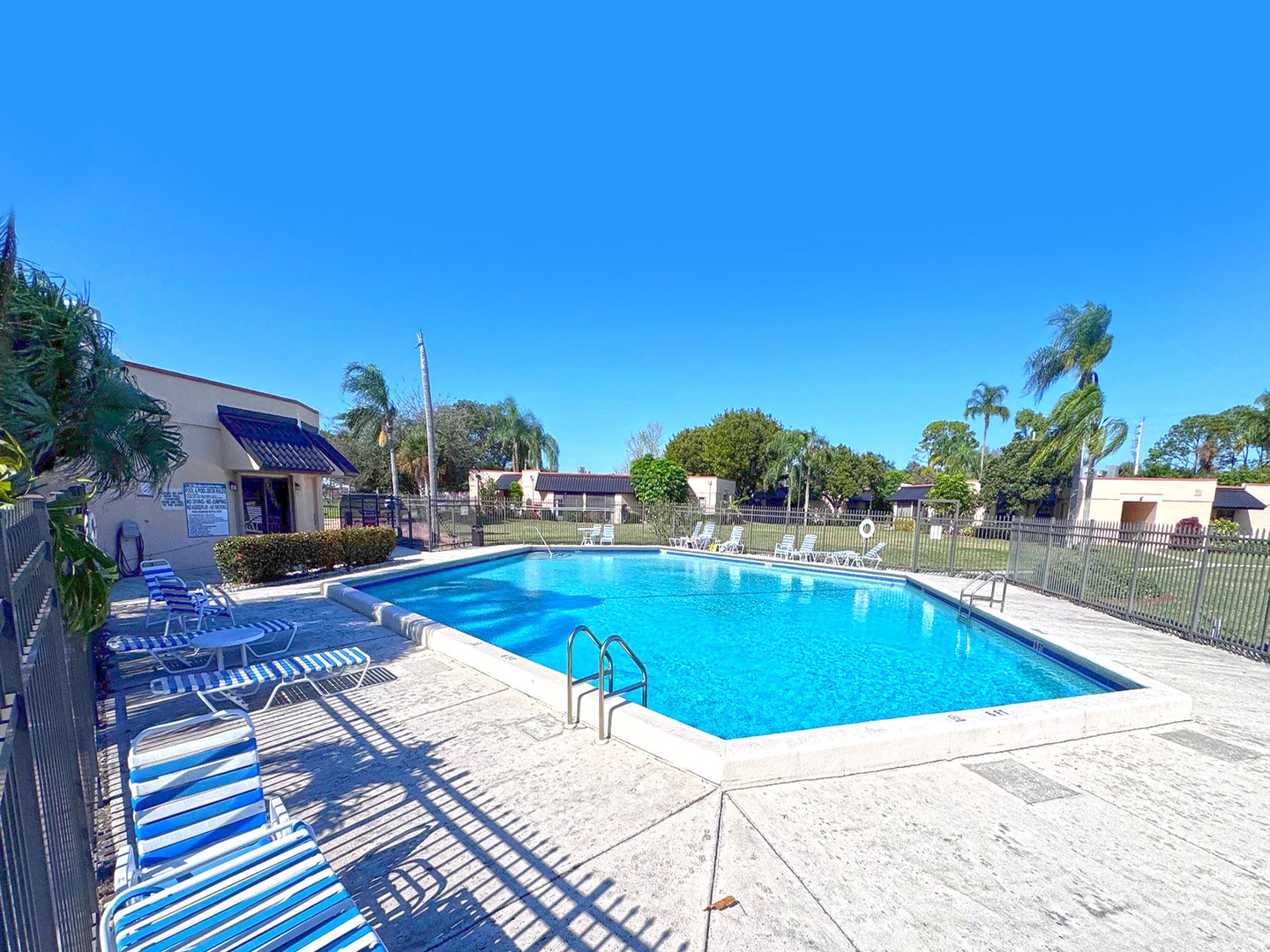 Sparkling community pool surrounded by tropical palms and comfortable loungers under endless blue skies.