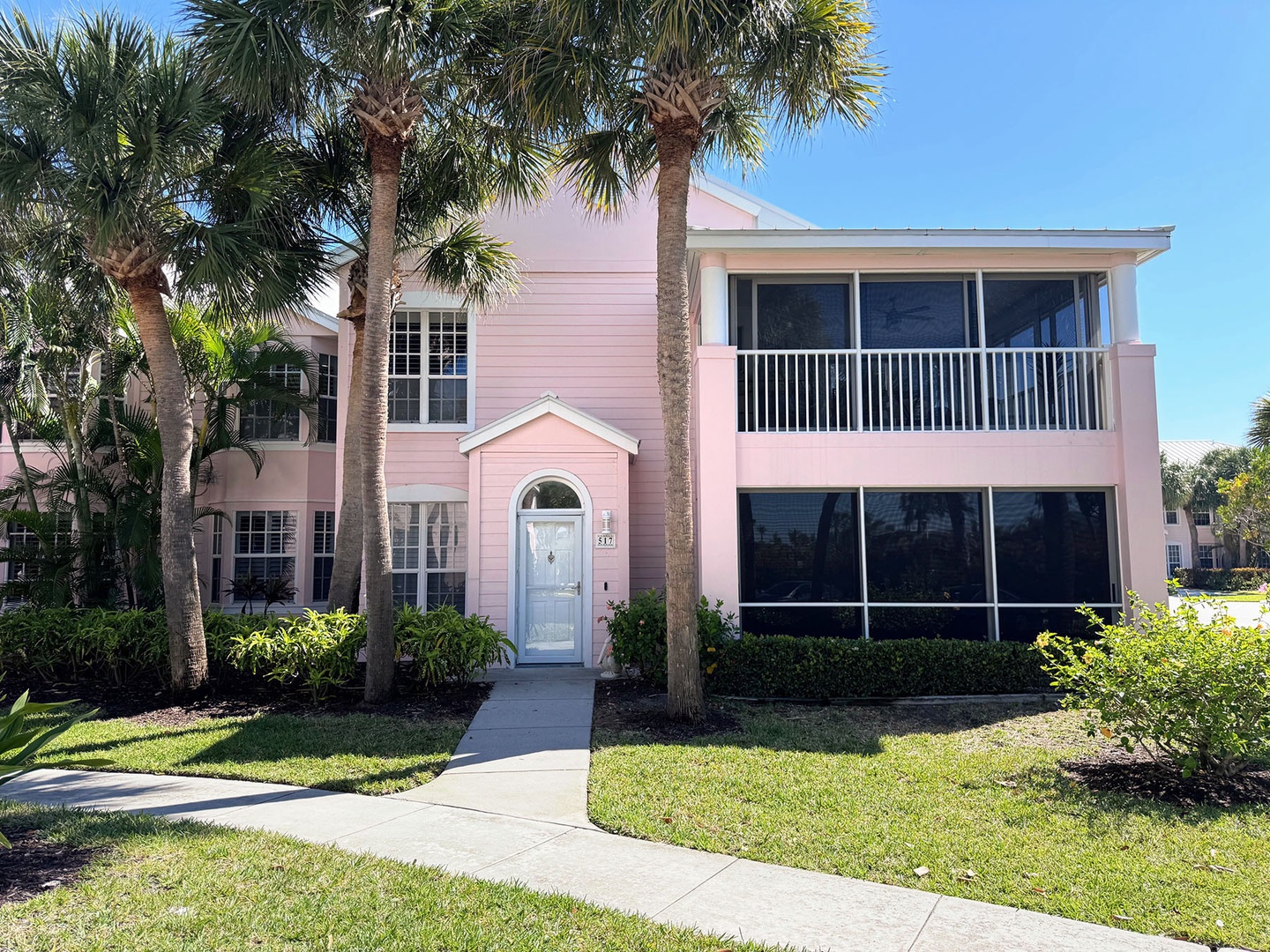 Charming pink ground floor coastal villa with tropical palm trees and enclosed porch just across the street from the beach.