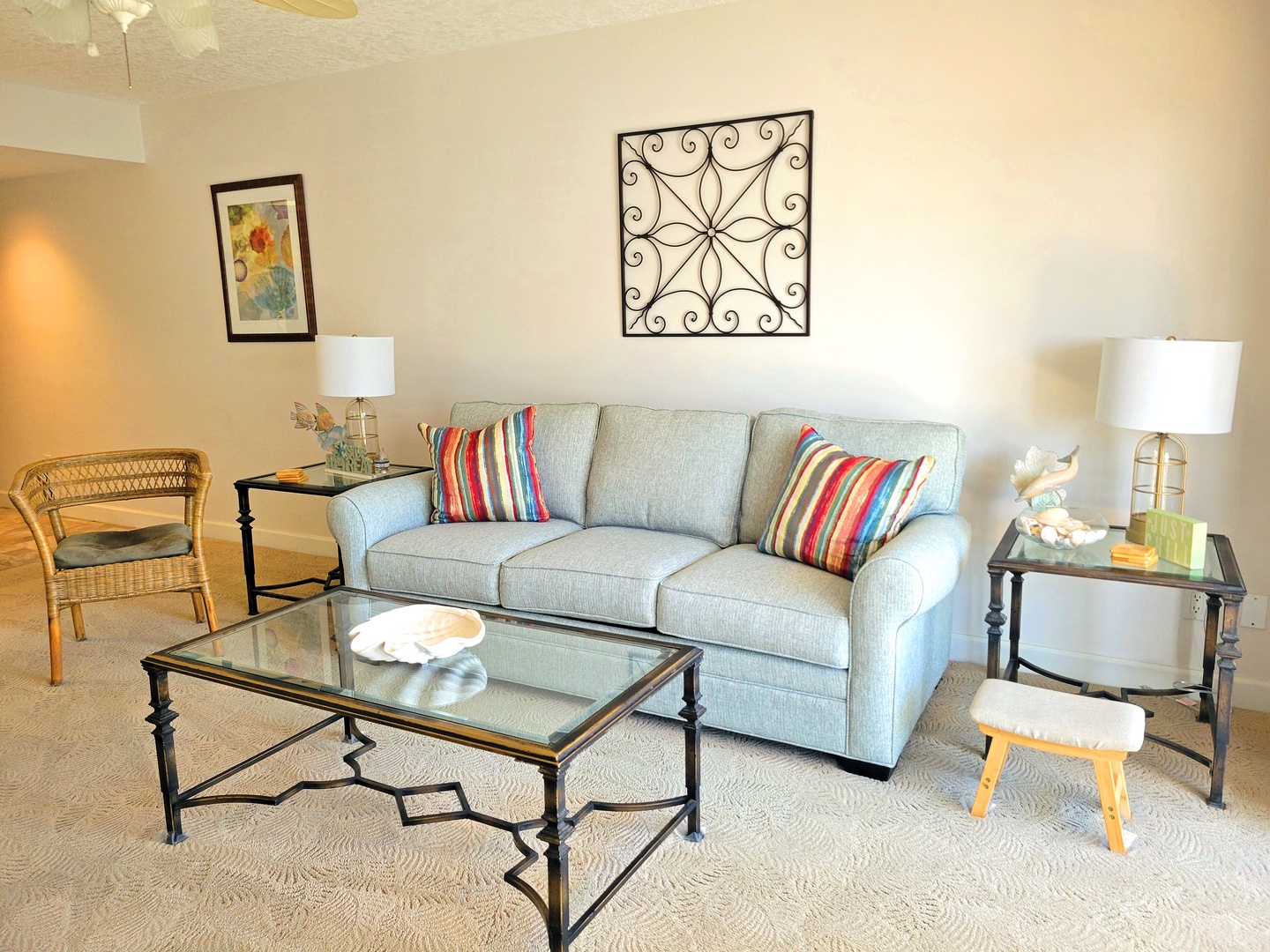 Sink into this comfortable sofa adorned with colorful striped pillows. The elegant glass tables and thoughtful decor create your perfect relaxation retreat.