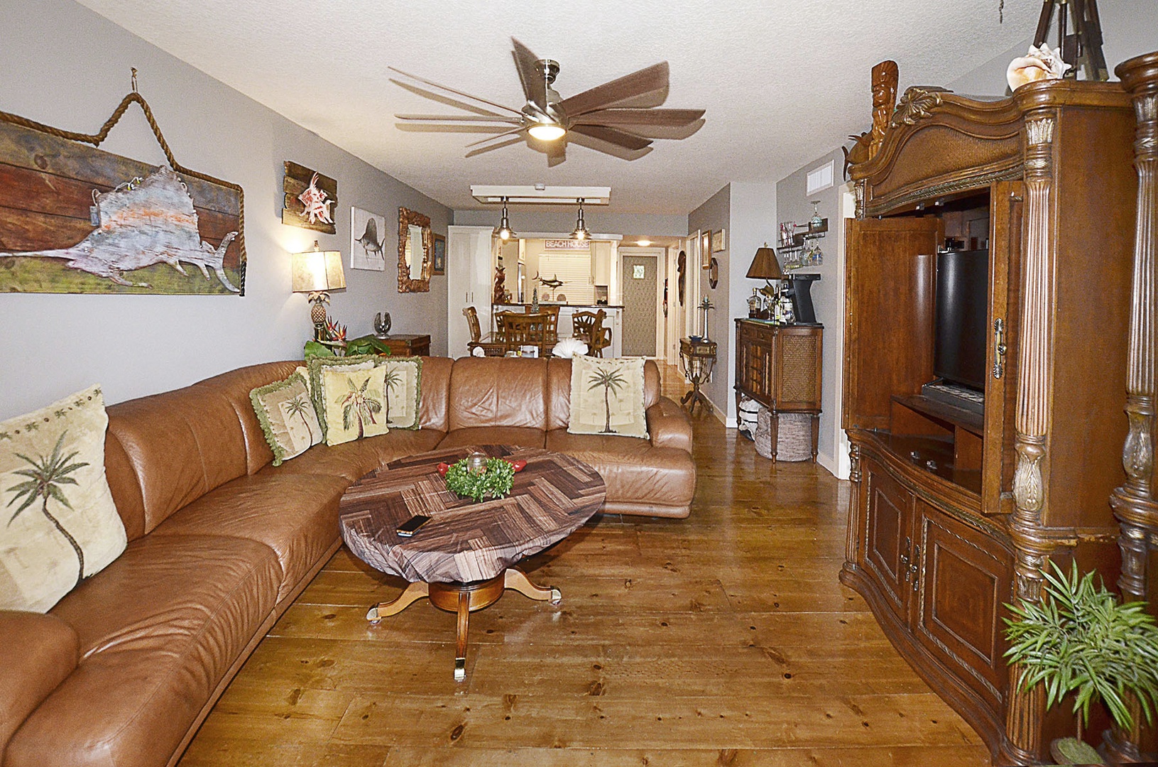 Living Room. Sink into plush leather seating while enjoying your favorite shows on the entertainment center in this inviting tropical-themed living space.