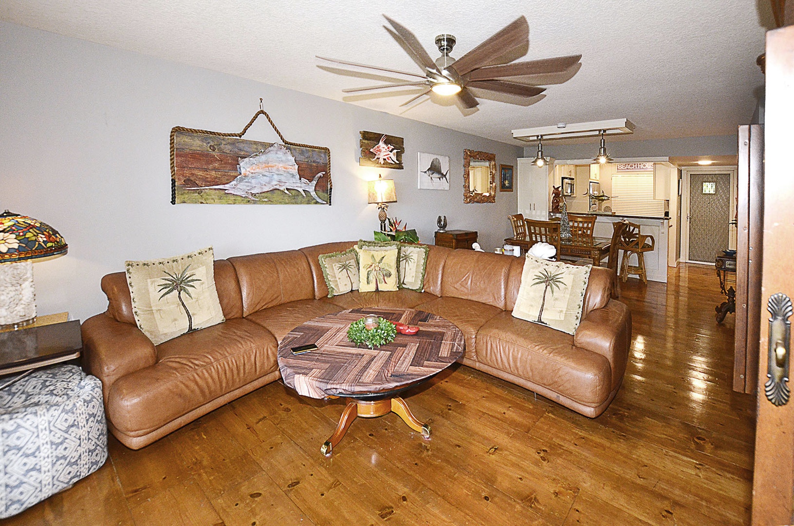 Living Room. Sink into the plush leather sectional where coastal charm meets comfort, with gleaming hardwood floors and tropical touches creating your perfect retreat.