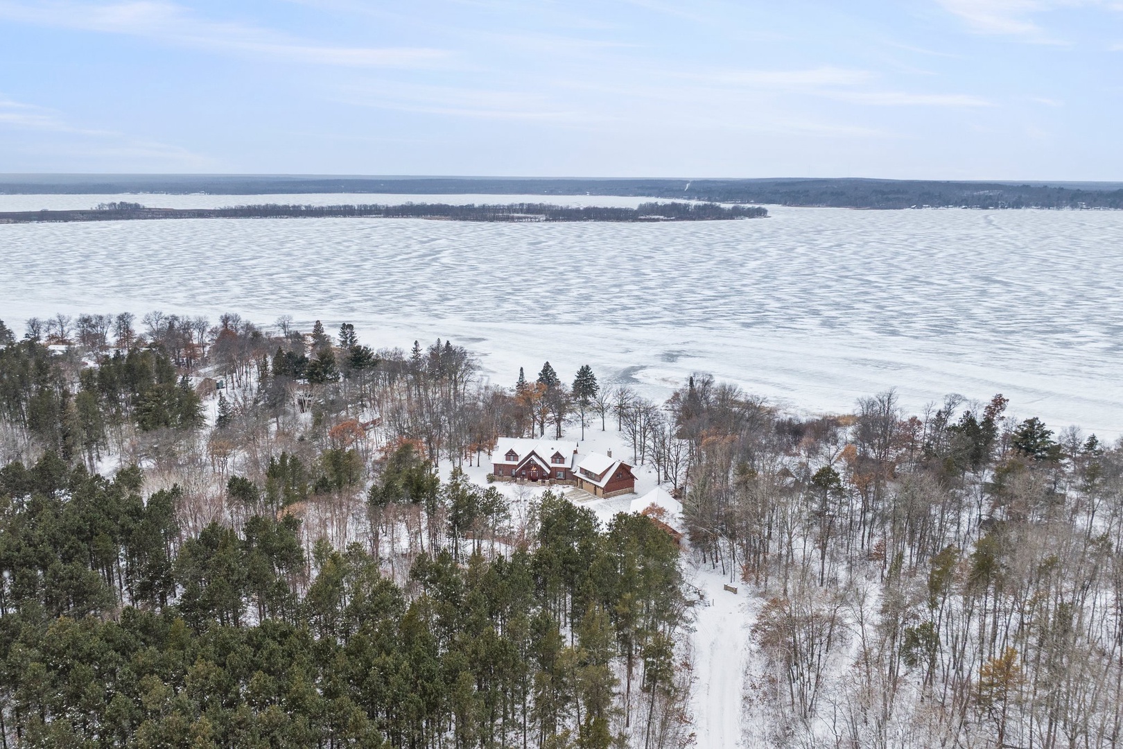 Stunning aerial winter vista reveals a secluded lakefront property nestled among snow-covered forests, offering pristine seasonal tranquility.