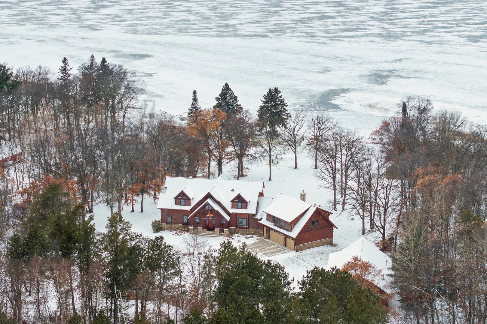 Stunning lakefront retreat nestled among snow-covered trees with panoramic winter views and peaceful waterfront setting.