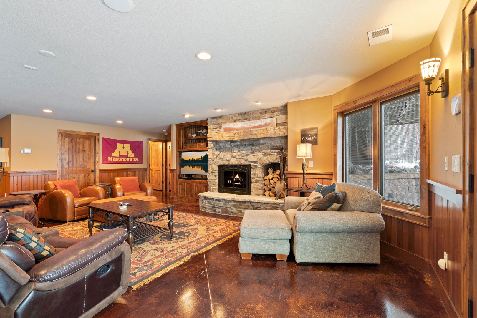 Unwind in your spacious living room where warm leather seating surrounds a crackling stone fireplace, creating the perfect atmosphere for memorable evenings together.