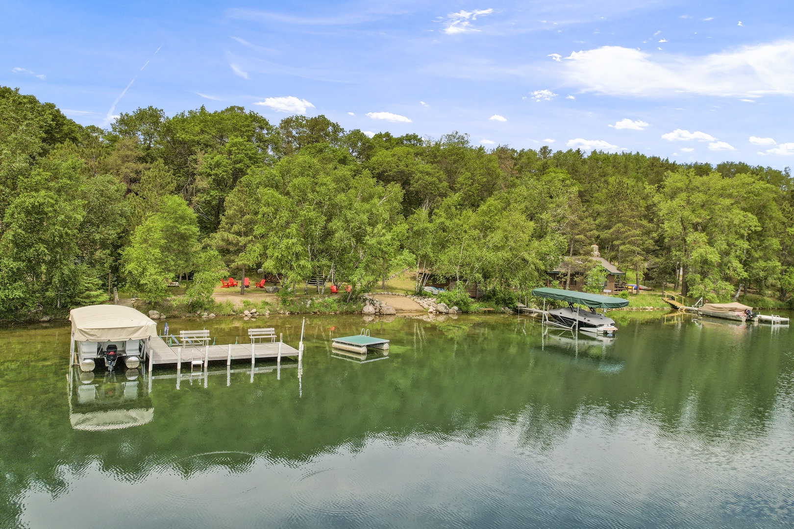 Peaceful lakefront setting with private docks, boats, and forested shores creating a serene waterside retreat.