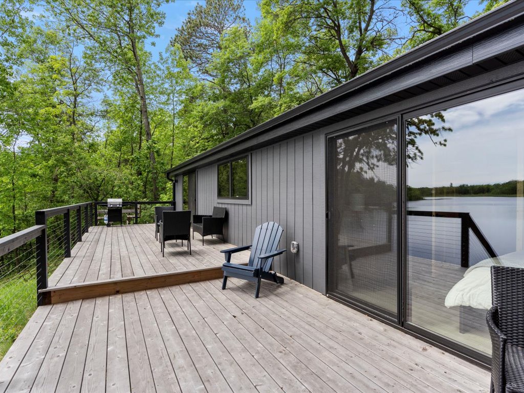 Modern lakefront retreat with a spacious deck overlooking tranquil waters, surrounded by lush greenery—perfect for peaceful mornings and scenic sunsets.