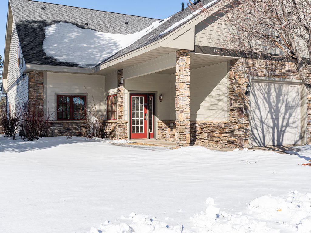 Modern vacation home featuring stone accents and covered entrance, nestled in a quiet setting