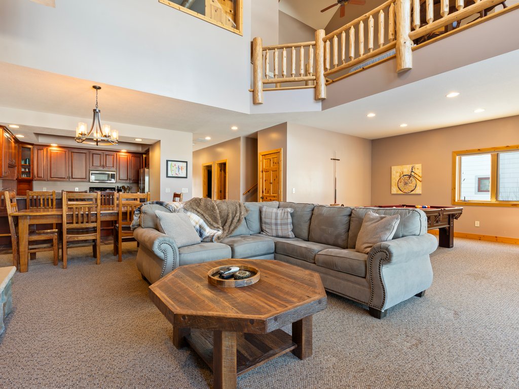 Unwind in your spacious living room featuring a plush sectional sofa, rustic coffee table, and open loft design that creates an airy, welcoming atmosphere.