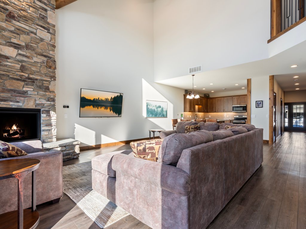 Unwind in your spacious living area where plush seating meets rustic stone fireplace warmth, creating the perfect retreat for cozy evenings together.
