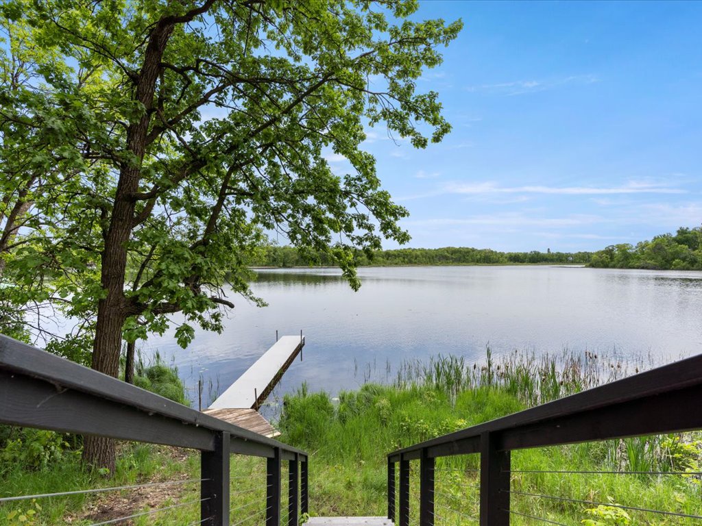 Private dock and serene lakefront access await. Steps lead to a peaceful waterside retreat with lush natural surroundings and calm waters perfect for kayaking or fishing.
