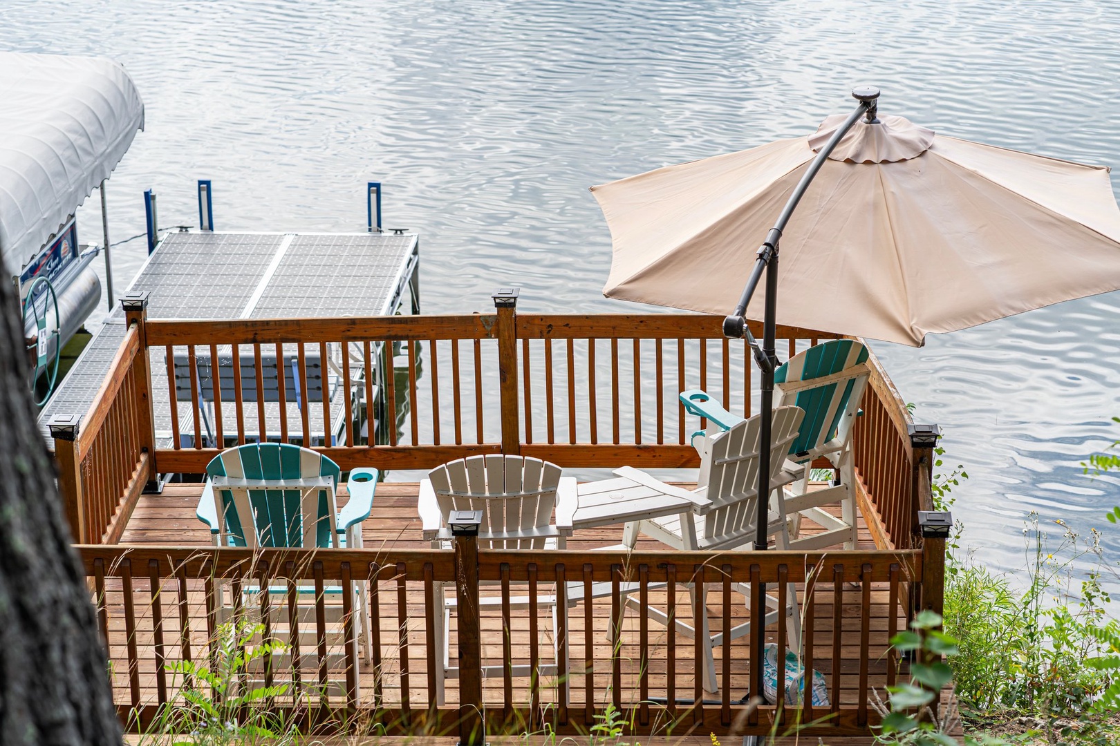 Relax on your private waterfront deck with Adirondack chairs and umbrella shade, overlooking serene lake waters.