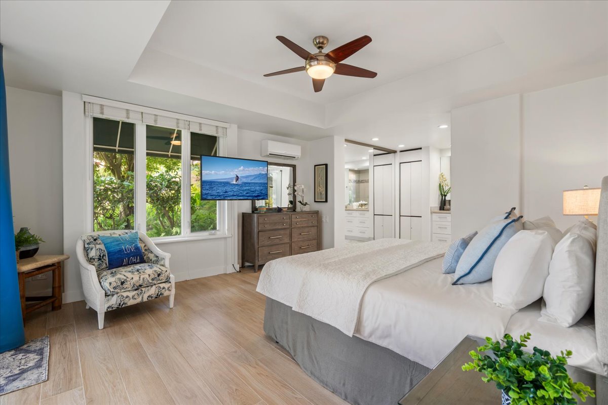 Unwind in your bright, airy retreat with crisp linens and a ceiling fan to keep you cool. Natural light pours through your window, framing lush greenery just outside.
