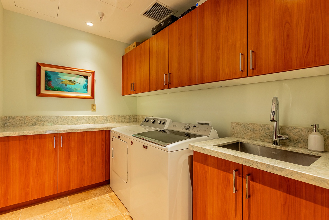 Your in-unit laundry room combines convenience and style, with warm wood cabinetry and ample counter space for folding and organizing.