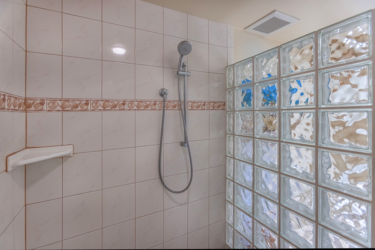 Your private shower features a handheld showerhead and elegant glass block wall that filters natural light while maintaining privacy.