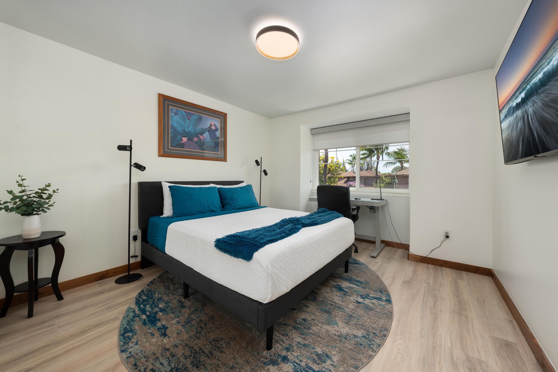 Your comfortable bedroom features a plush bed with vibrant blue accents and palm tree views through the window.