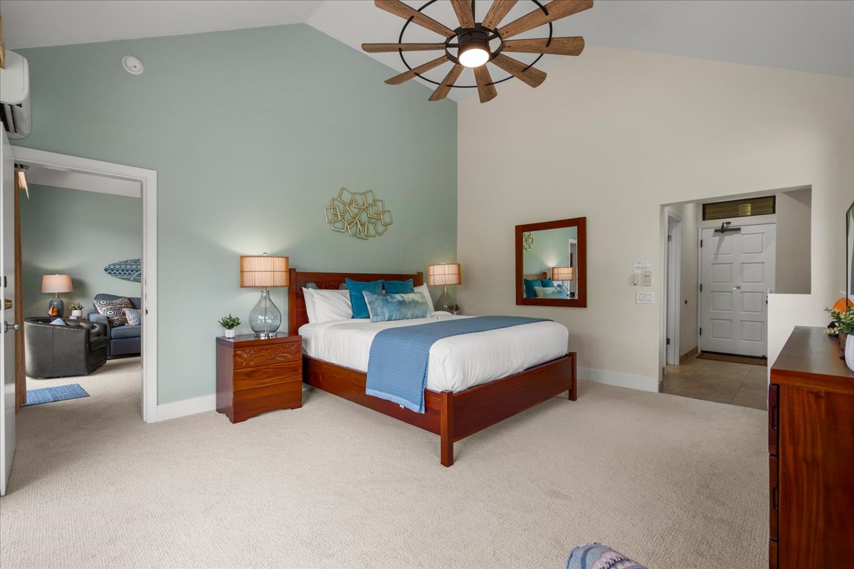 Picture yourself unwinding in this serene bedroom featuring a plush bed dressed in crisp linens and soothing blue accents. Warm bedside lamps and a modern windmill-style ceiling fan create inviting comfort for restful nights.