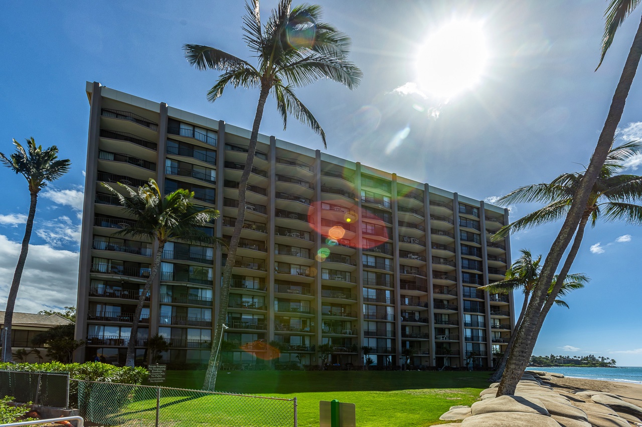 Beachfront property with swaying palms and manicured lawn, just steps from the sandy shore and sparkling ocean waters.
