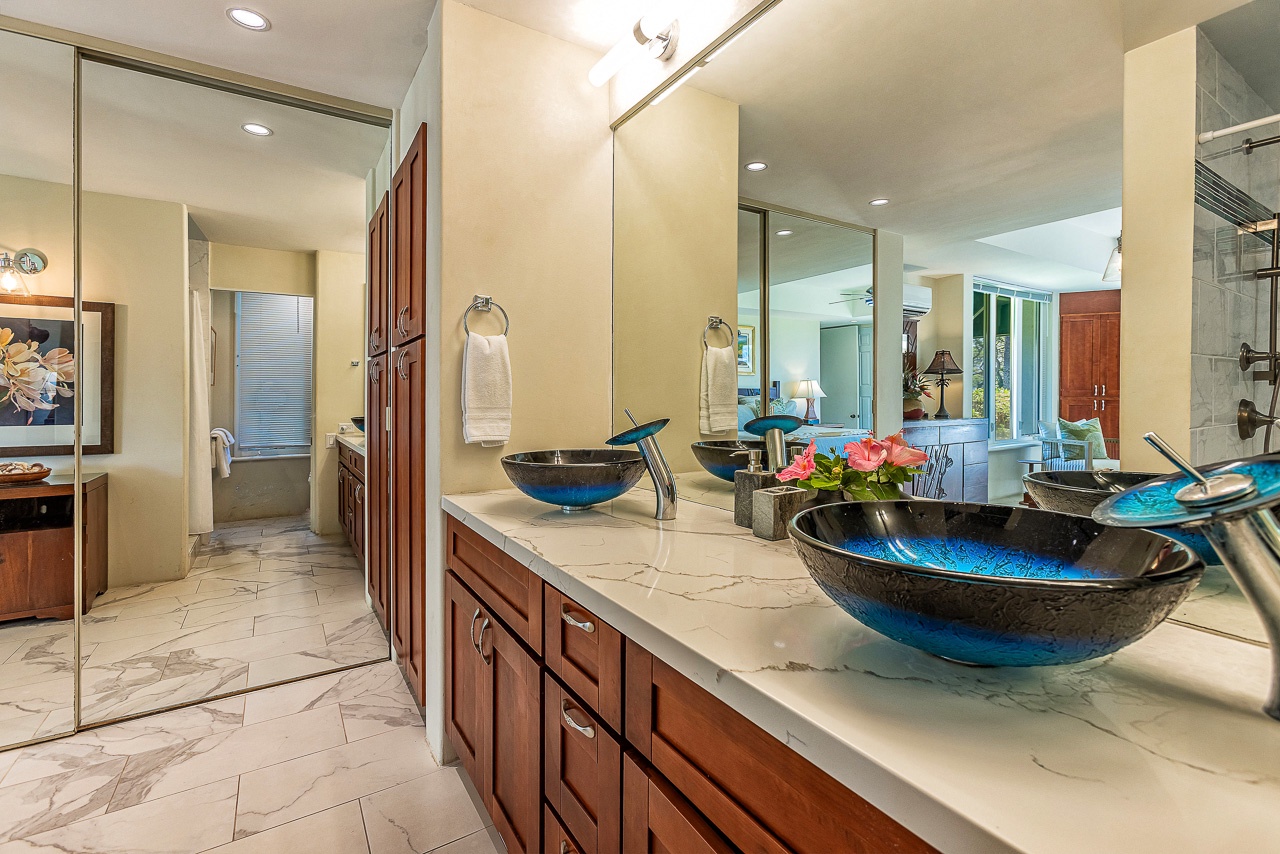 Step into your spa-inspired en-suite, where striking blue vessel sinks and polished marble counters invite you to unwind and refresh after island adventures.