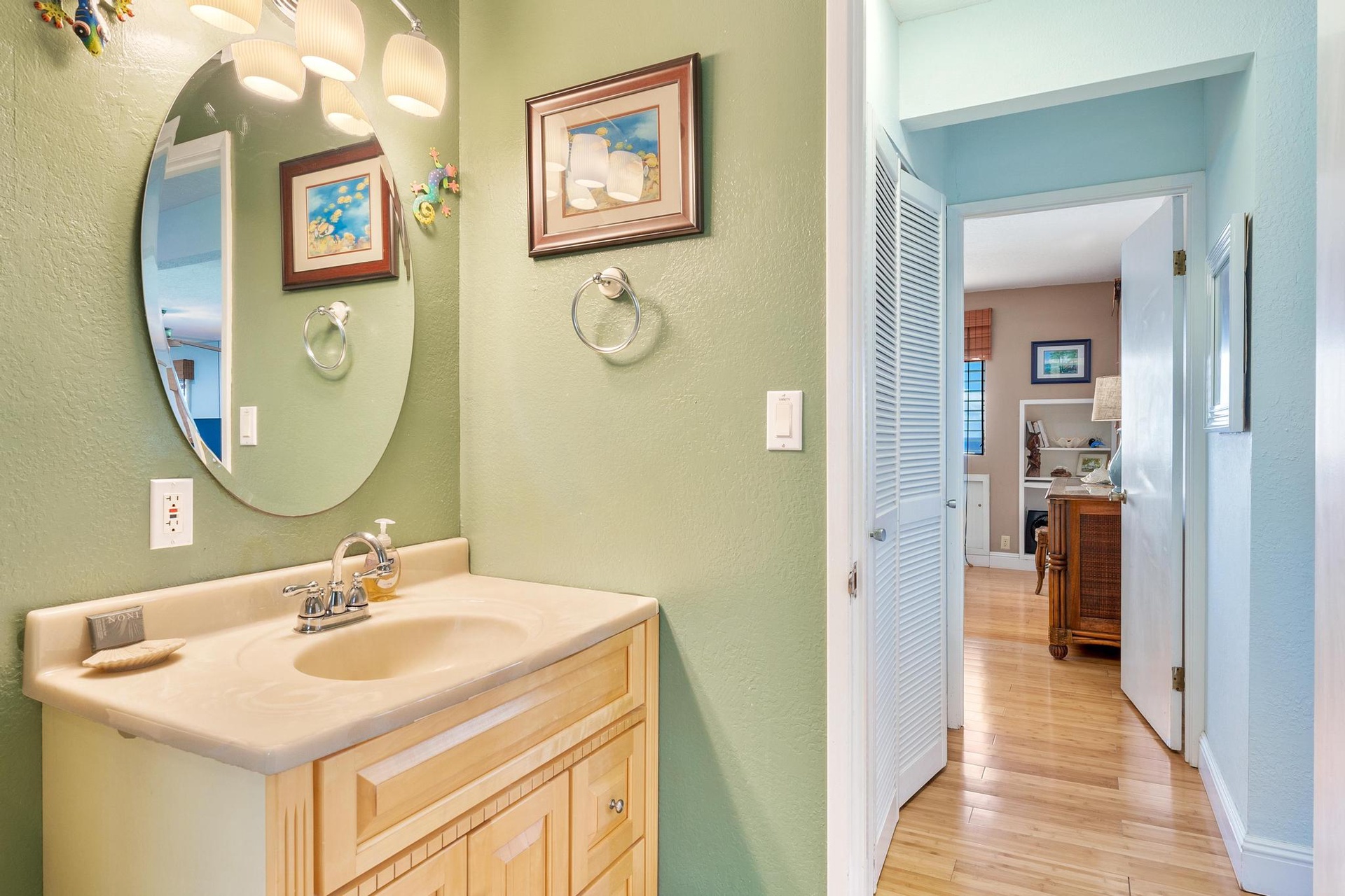 Guest bathroom features coastal artwork and soothing green walls that make your morning routine feel like a mini retreat.