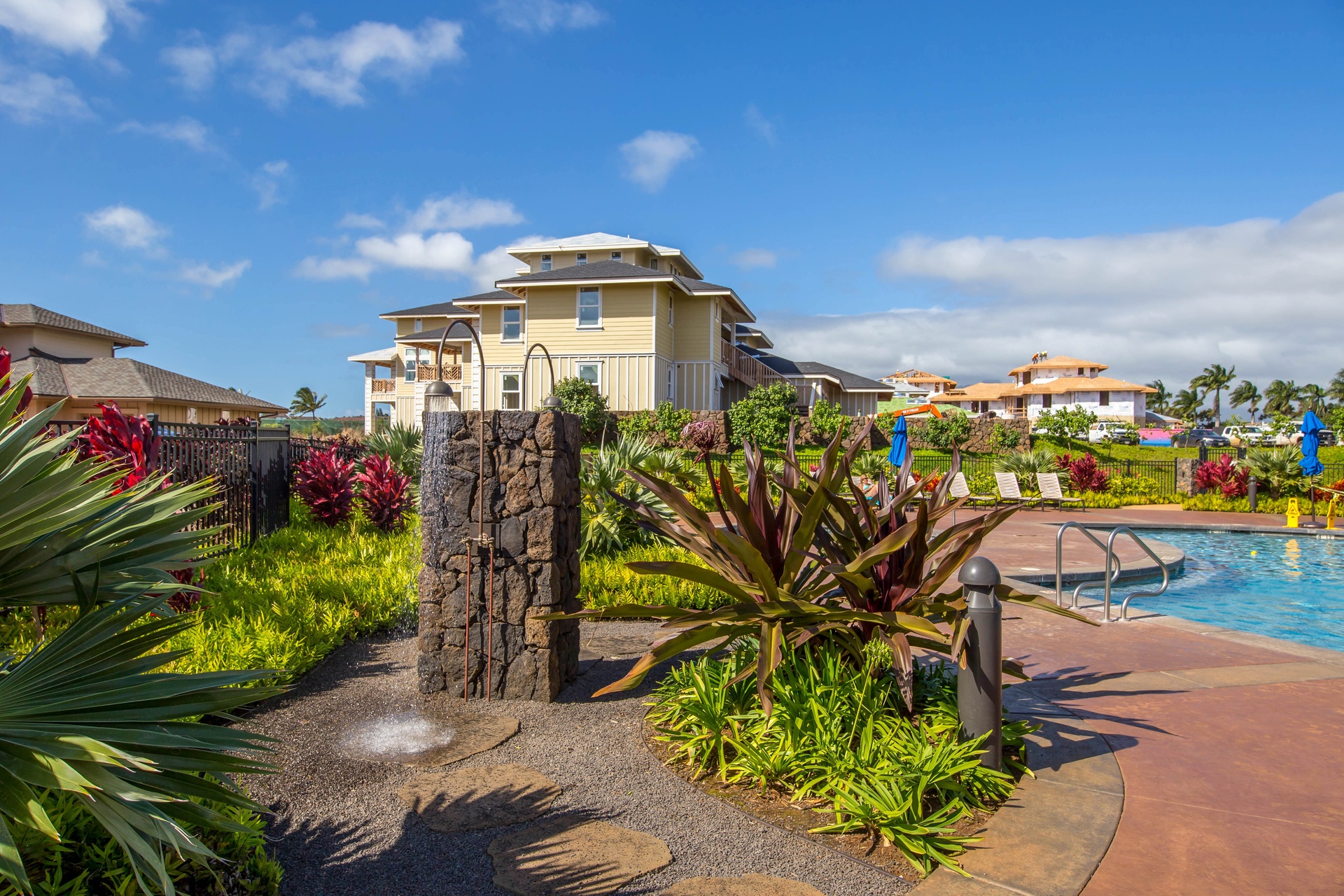A tropical resort community featuring lush landscaping, sparkling pool, and contemporary architecture under brilliant Hawaiian skies.