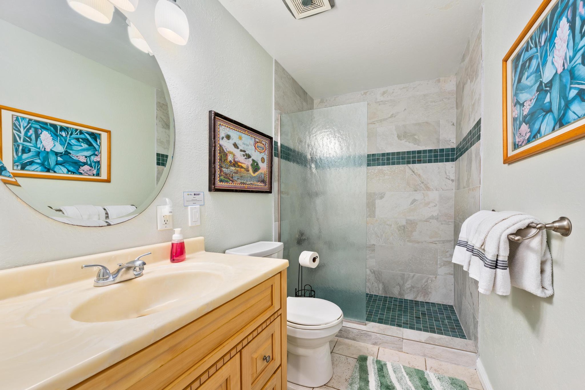 Refresh in your private bathroom ensuite with a spacious tiled shower, marble accents, and tropical artwork creating a serene spa-like atmosphere.