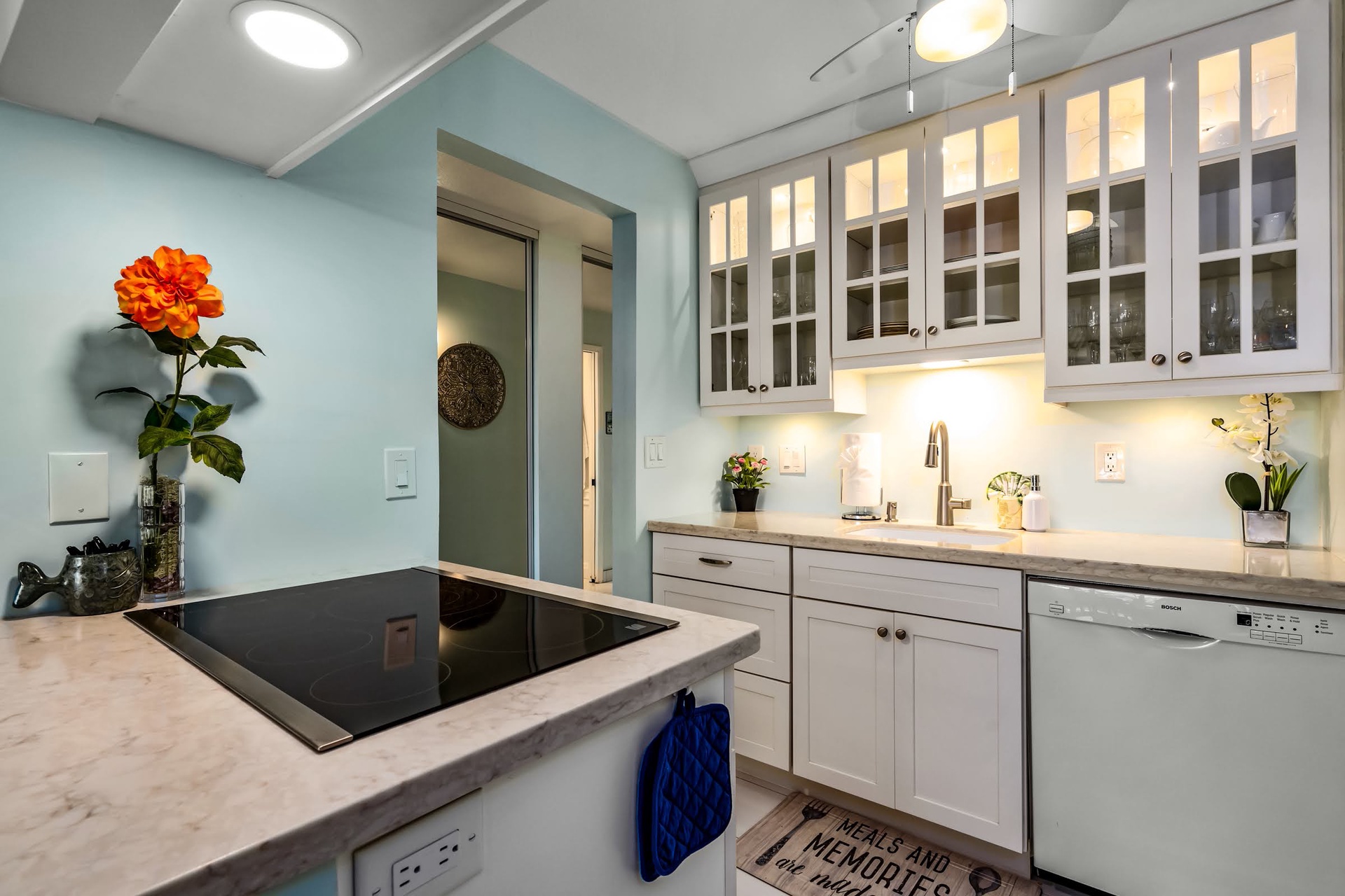 Step into your bright, fully-equipped kitchen with sleek marble countertops, modern appliances, and elegant glass-front cabinetry, ready for your culinary adventures.