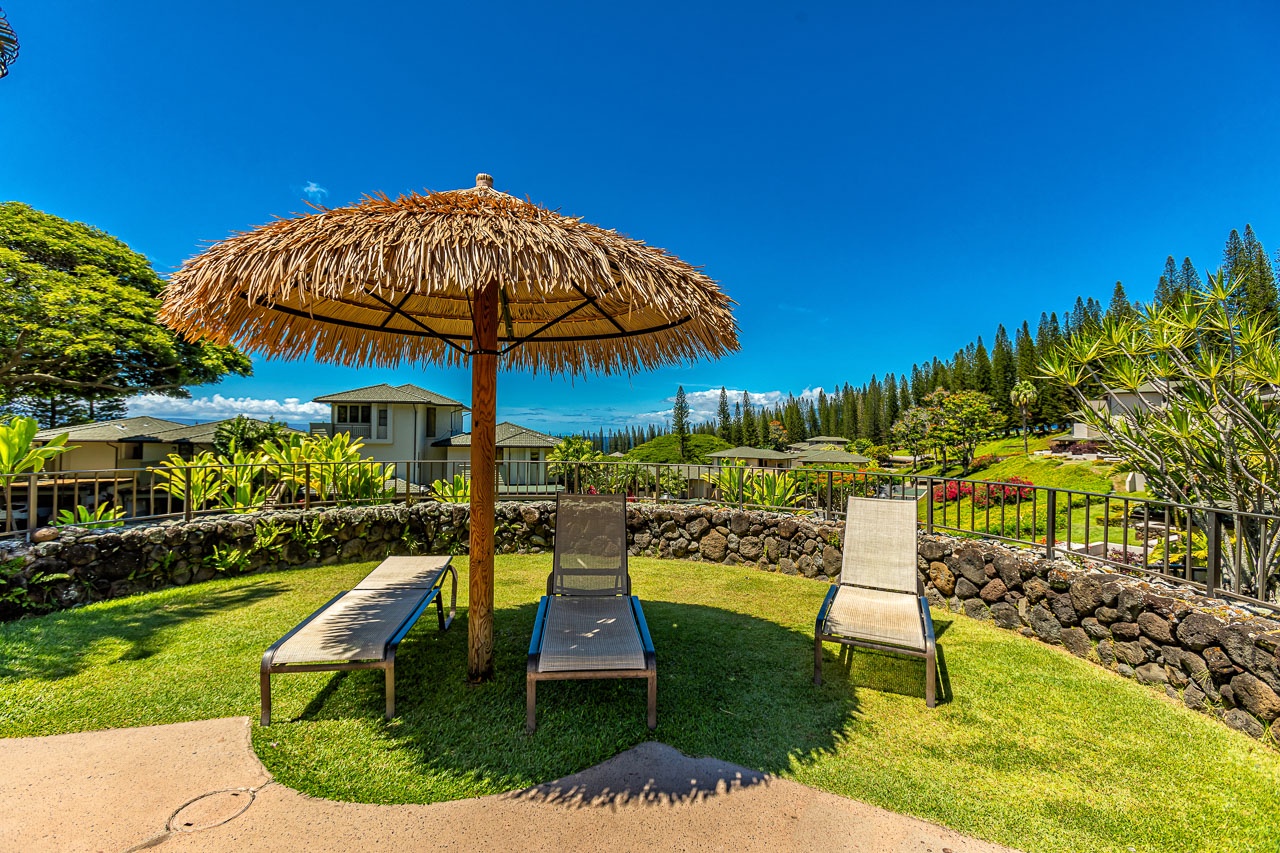 Private outdoor lawn area with loungers under a thatched palapa umbrella, surrounded by tropical gardens and mountain views—a perfect island retreat for relaxation and sunshine.