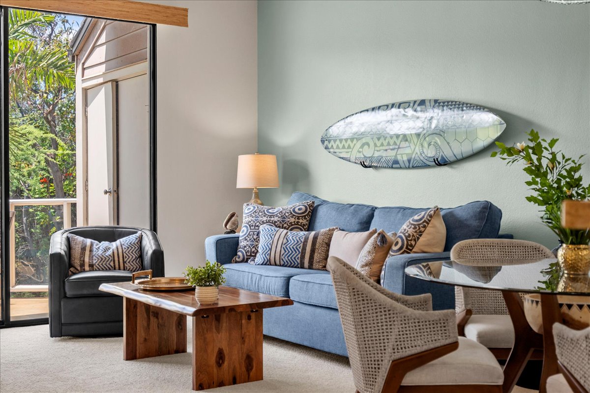 Settle into your coastal-inspired living space where natural light streams through the glass doors, framing lush greenery beyond. Sink into the plush sofa surrounded by beach-inspired decor that invites total relaxation.