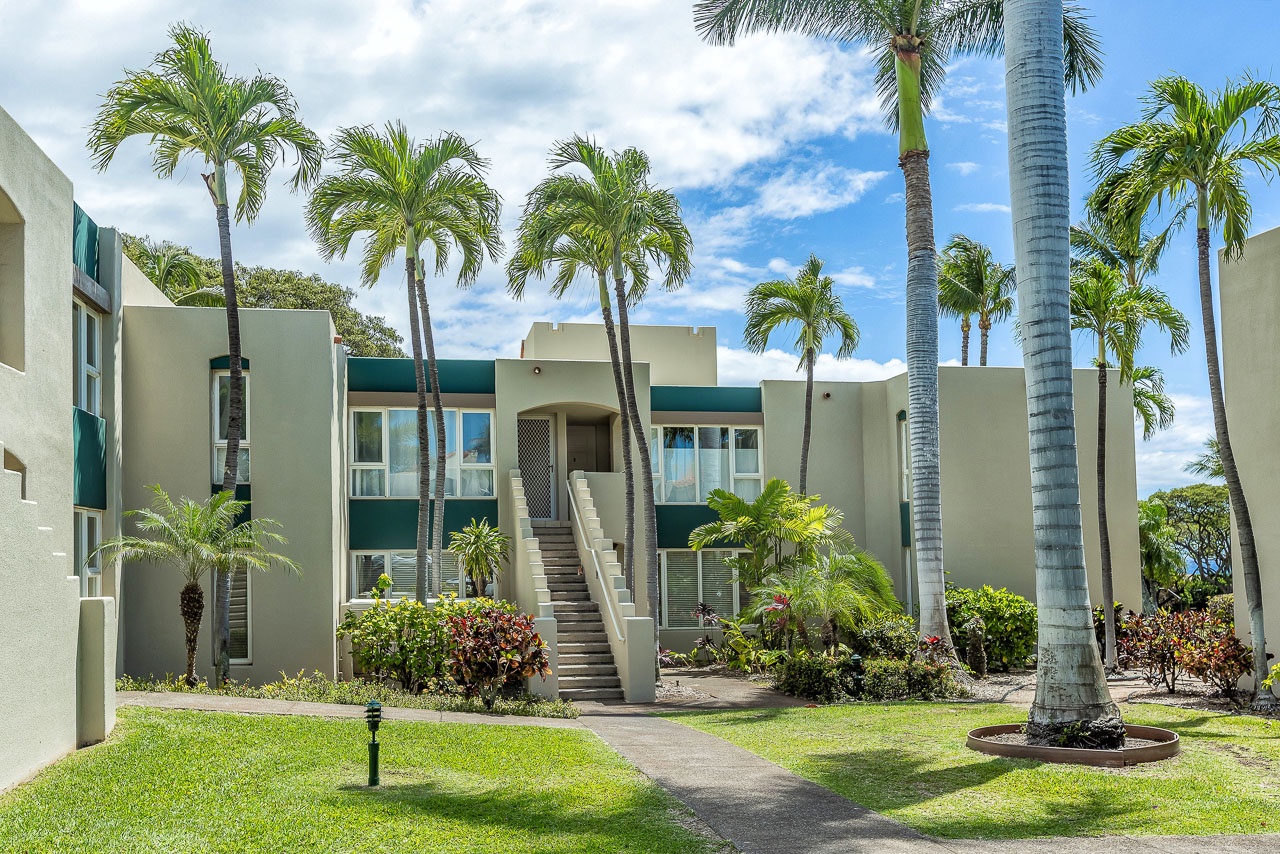 Modern tropical property surrounded by lush landscaping and towering palms, offering a serene island retreat experience.
