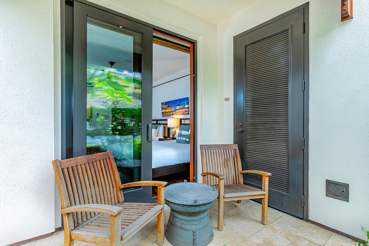 Step outside to your private balcony and settle into the warm wooden chairs for a quiet moment. Through the glass doors, lush tropical greenery and a peaceful pool await.