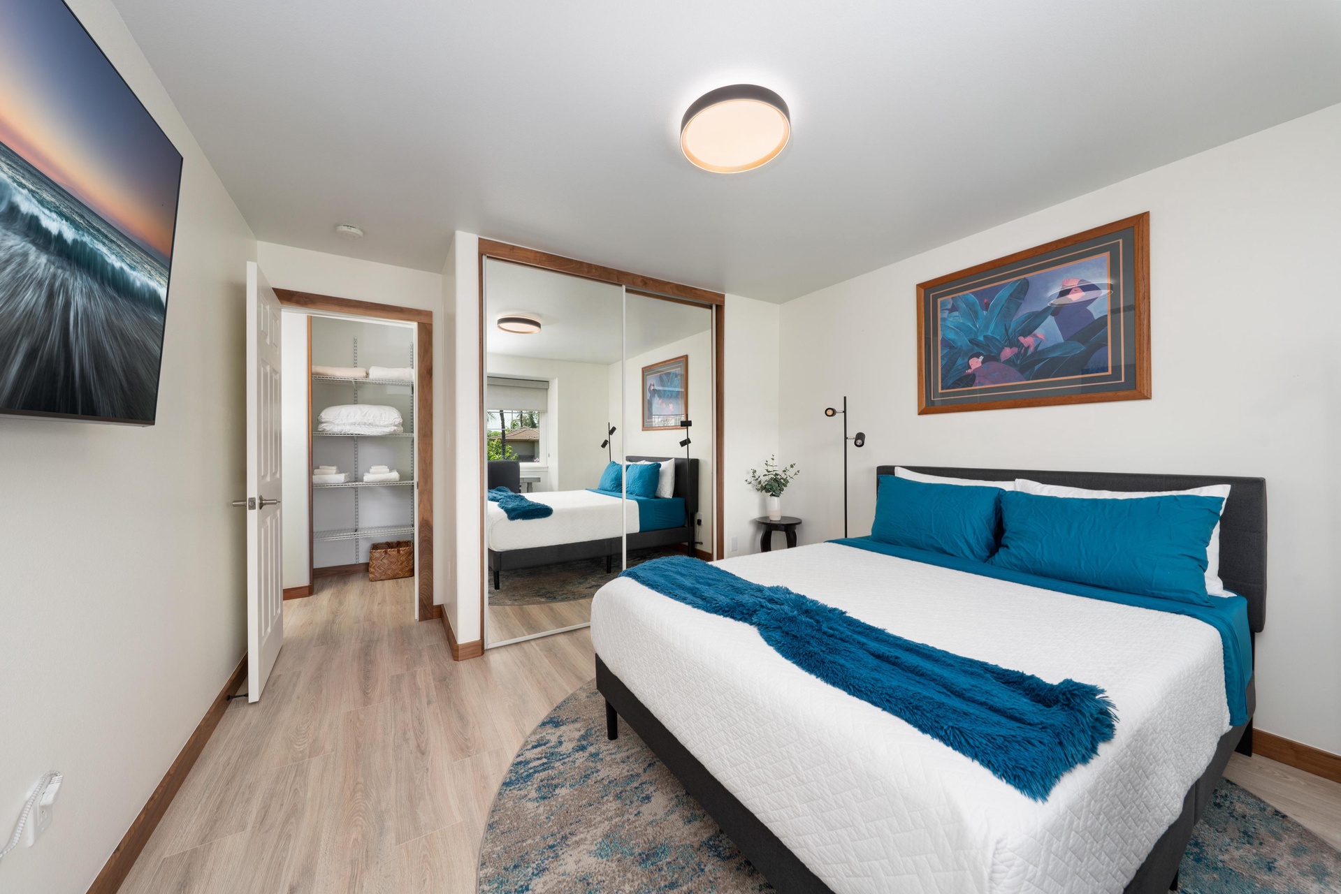 Sink into crisp white linens accented with deep teal touches in your serene bedroom sanctuary, complete with thoughtful storage and ocean-inspired artwork.