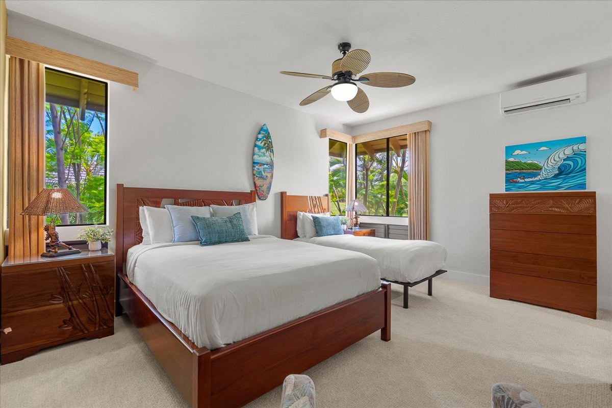 You'll love waking up in this serene bedroom, where tropical breezes drift through large windows revealing lush greenery. Two plush beds, coastal surf art, and rich wooden furnishings create your perfect island escape.