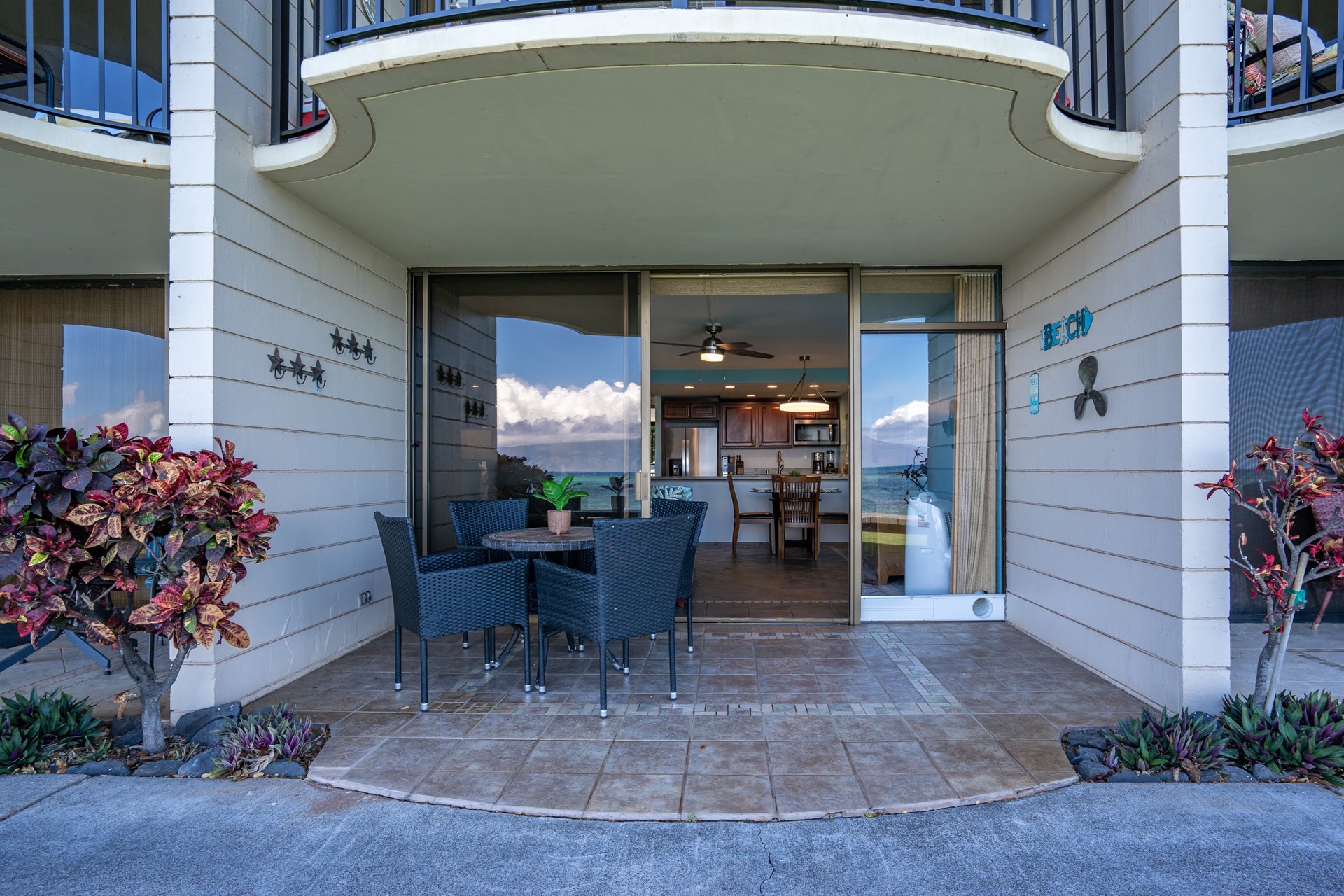 With woven dining chairs and vibrant tropical plantings, this space opens seamlessly to your kitchen and invites you to dine with stunning water views just beyond.