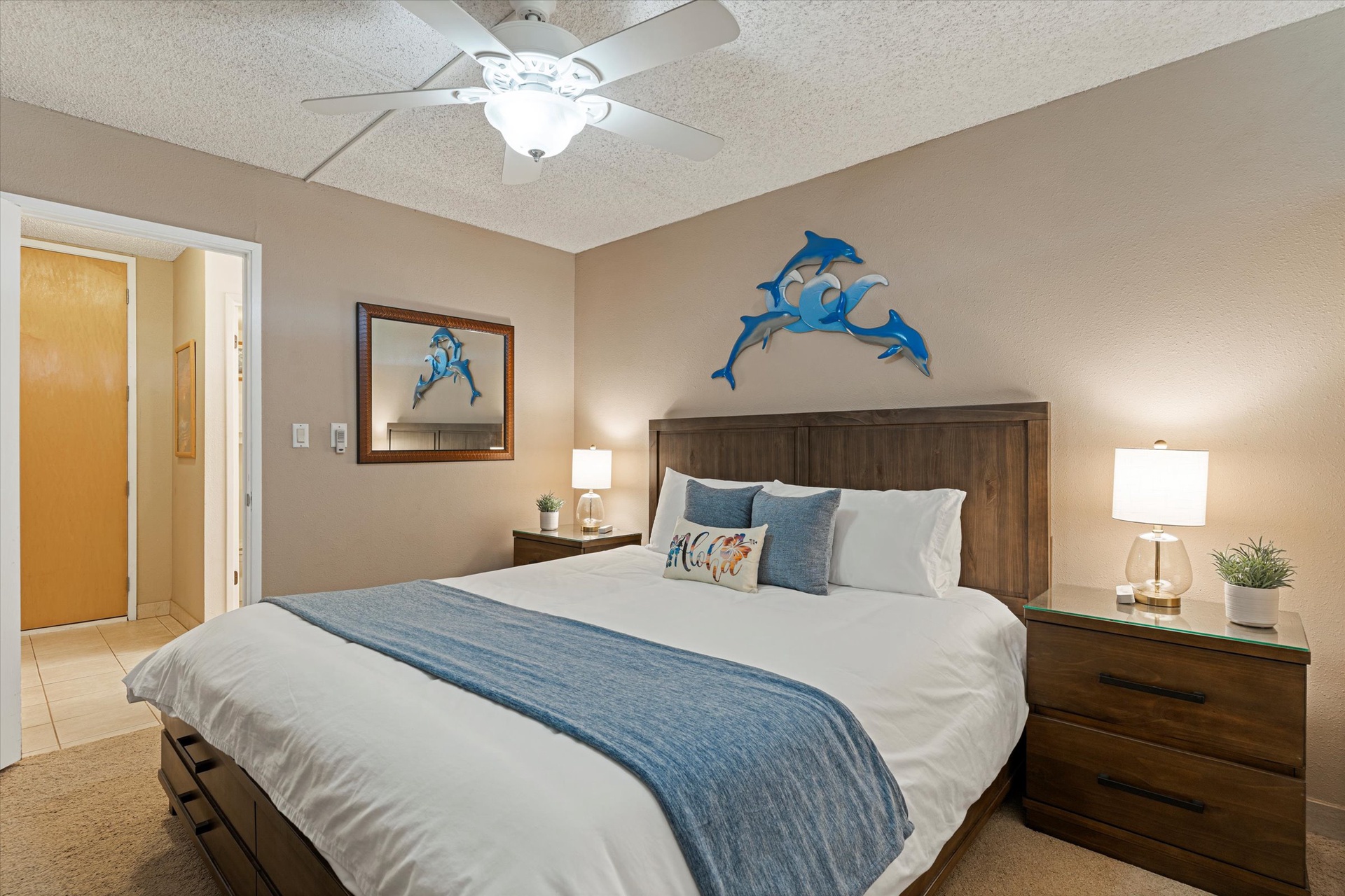 Sink into your comfortable bed beneath a coastal-themed ceiling fan. Blue dolphin art and soft bedside lighting create a relaxing seaside escape for your vacation.