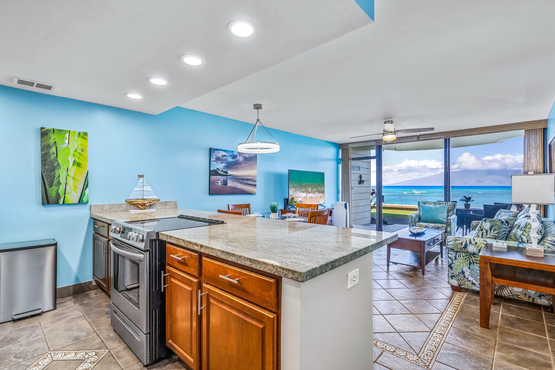 Open-concept sanctuary where kitchen, dining, and living areas flow together with stunning ocean views through floor-to-ceiling glass doors.