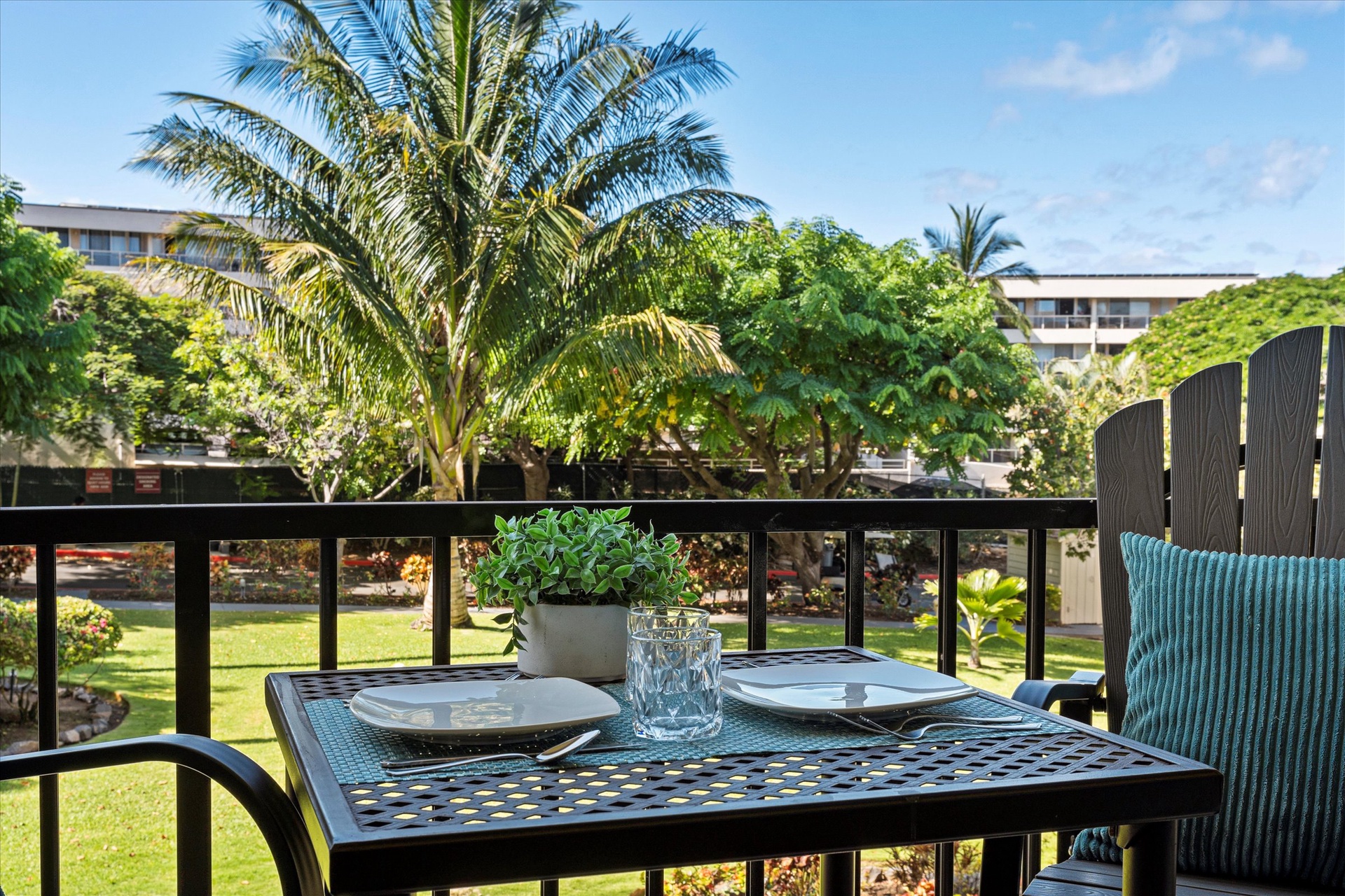 Picture yourself sipping morning coffee at this inviting balcony table, surrounded by swaying palms and lush tropical gardens. Your private outdoor retreat overlooks serene grounds, perfect for unwinding.