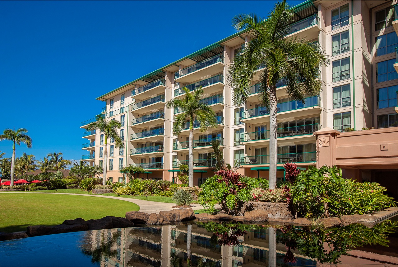 A welcoming tropical resort building with private balconies nestled among lush landscaping.