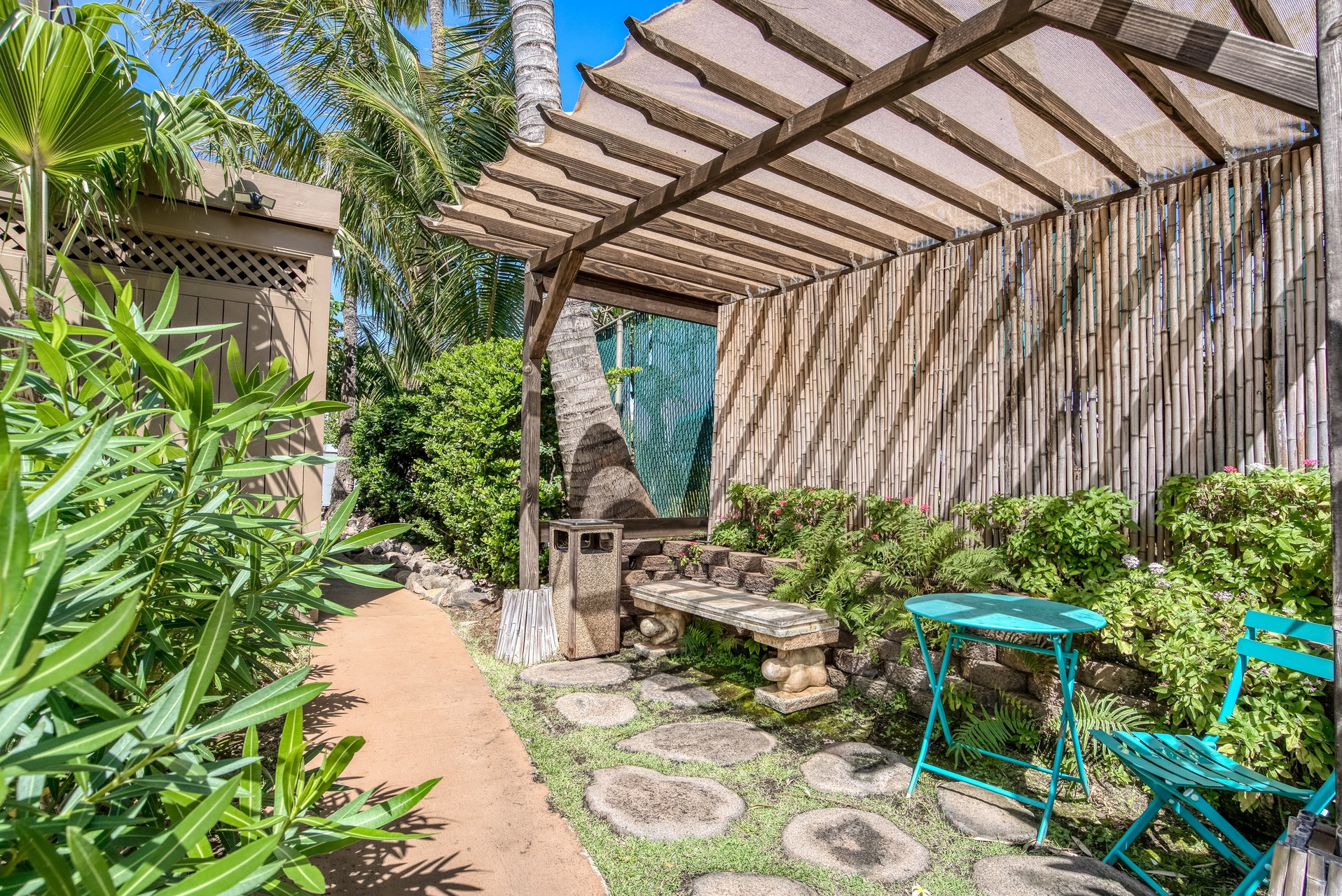 A shaded garden retreat with BBQ, lush greenery, and colorful seating perfect for morning coffee or evening relaxation.