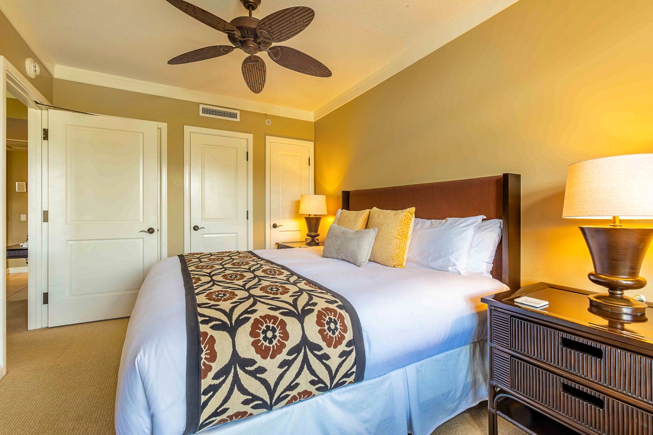 Sink into crisp white linens and rest easy beneath the gentle breeze of your ceiling fan, surrounded by warm golden tones that invite total relaxation.