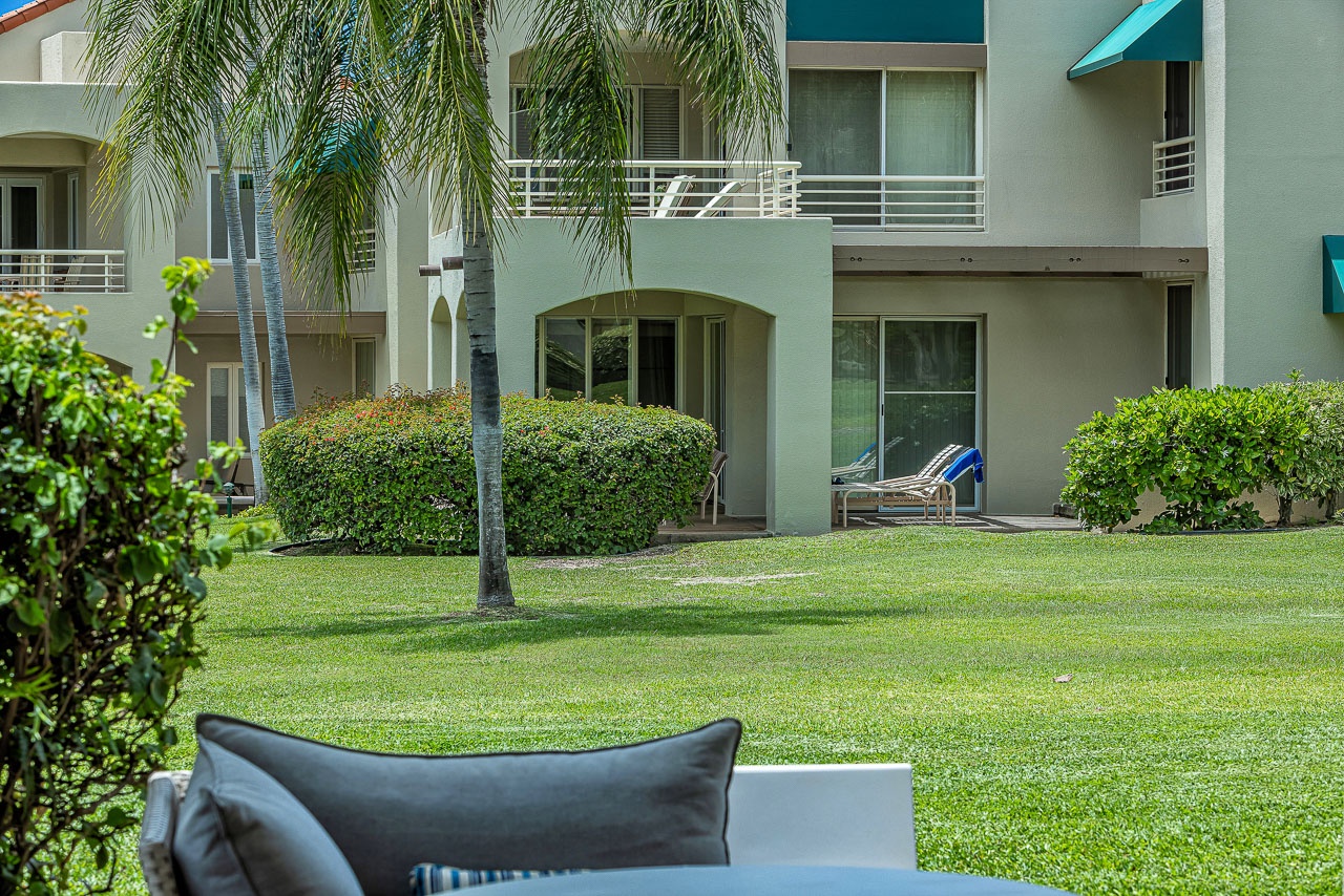 Relax in your private garden space, framed by lush greenery and swaying palms, just steps from your ground-floor patio retreat.