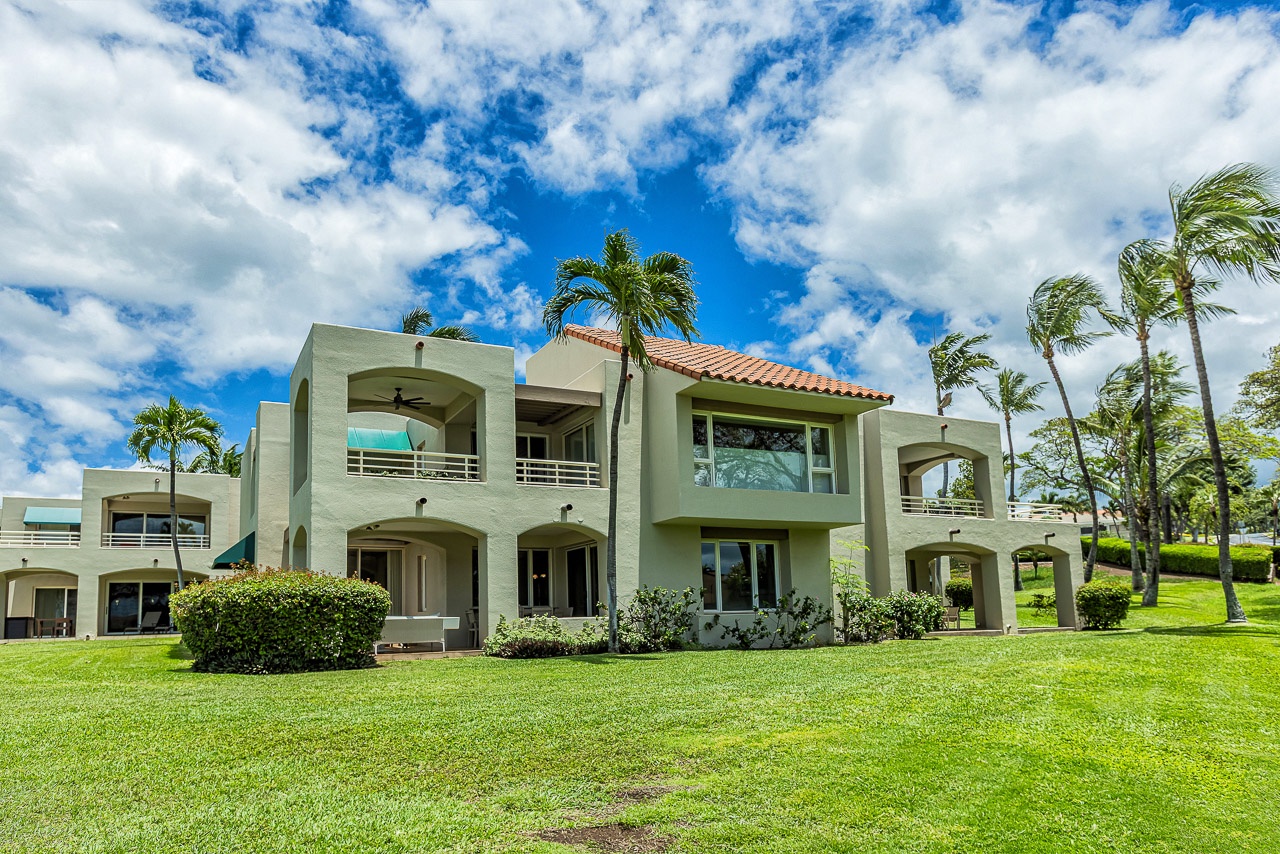 Tropical resort property surrounded by swaying palm trees and manicured lawns, framed by vibrant blue skies and sunshine.