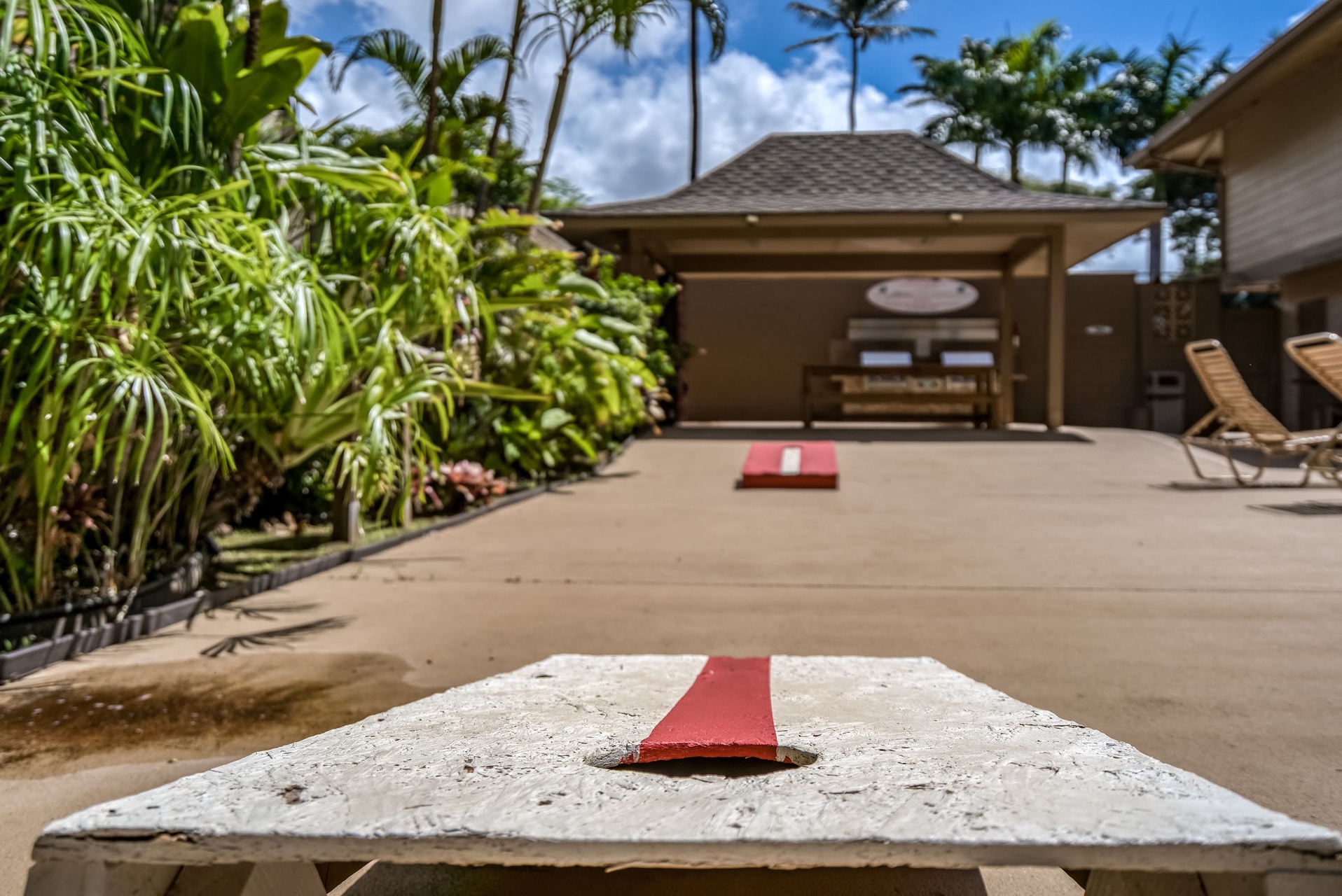 A cornhole setup awaits your friendly competition surrounded by lush tropical gardens and swaying palms. Pair your outdoor games with lounging under blue skies—your Hawaiian escape includes plenty of fun and relaxation.