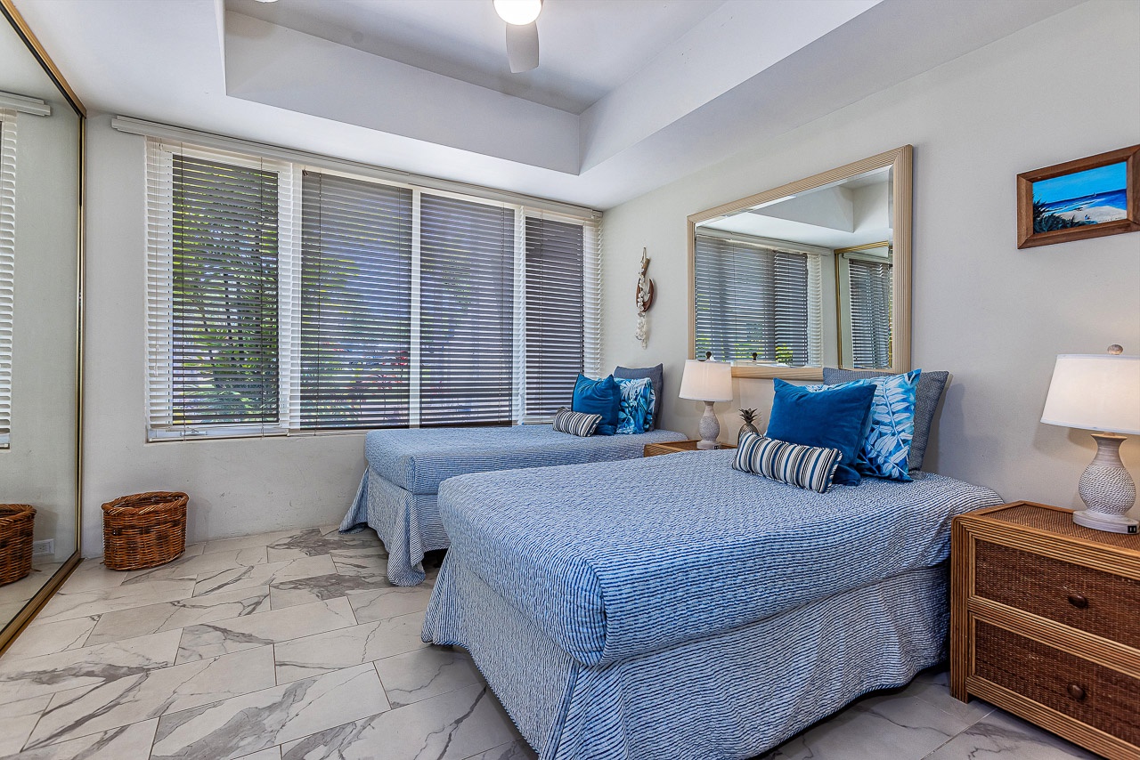 Relax in your airy bedroom with twin beds dressed in coastal blue linens, natural wicker furnishings, and soft light filtering through the windows—your restful sanctuary awaits.