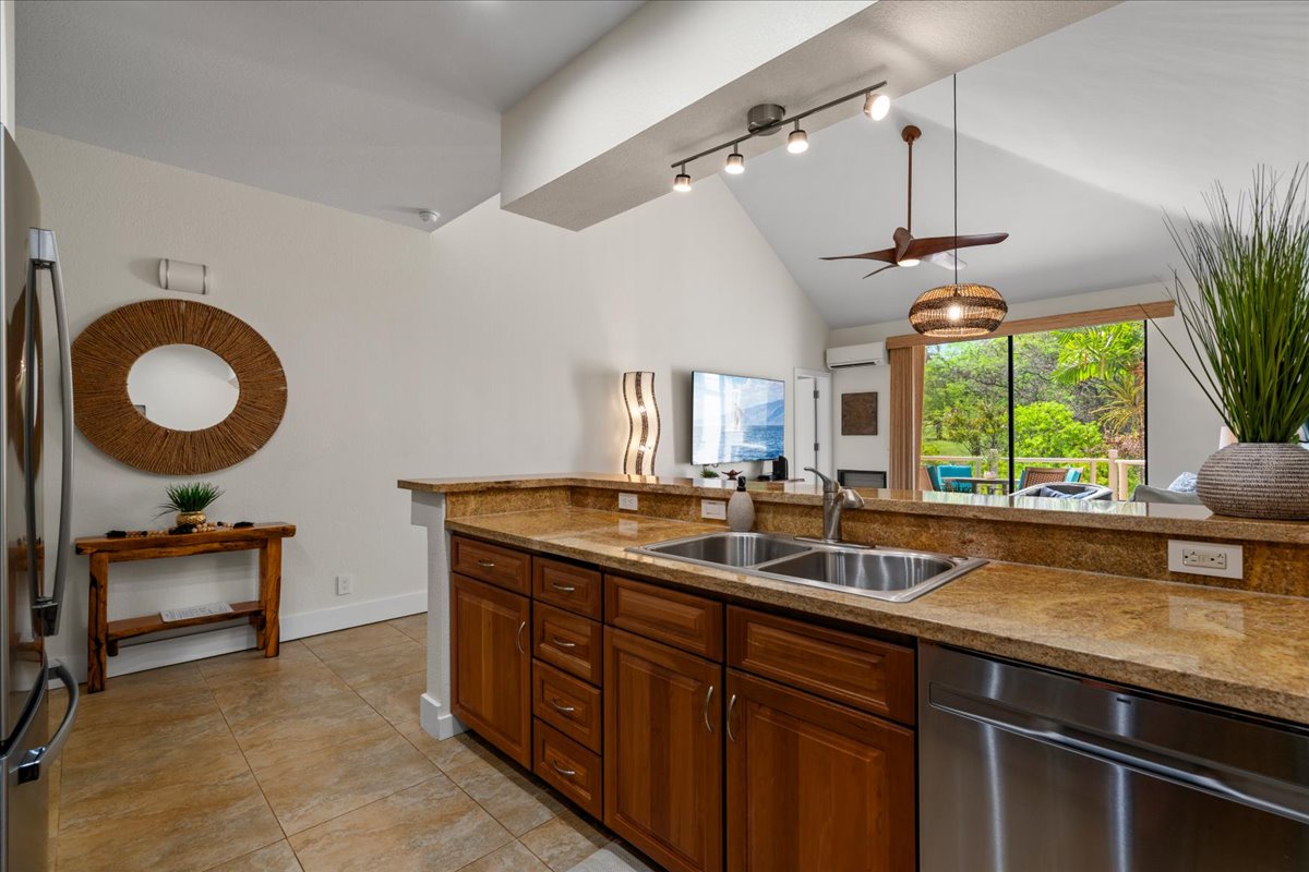 Cook your favorite meals in this fully equipped kitchen featuring granite countertops, warm wood cabinetry, and stainless steel appliances. Large windows flood the space with natural light and views.